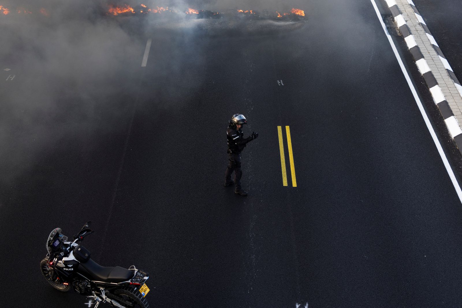 An Israeli policeman gestures as he opens a main road following a demonstration by protestors, which blocked the road, demanding the immediate end of the war and the release of all hostages who were kidnapped during the deadly October 7, 2023, attack on Israel by Hamas, in Yakum near Tel Aviv, Israel, August 26, 2025. REUTERS/Nir Elias