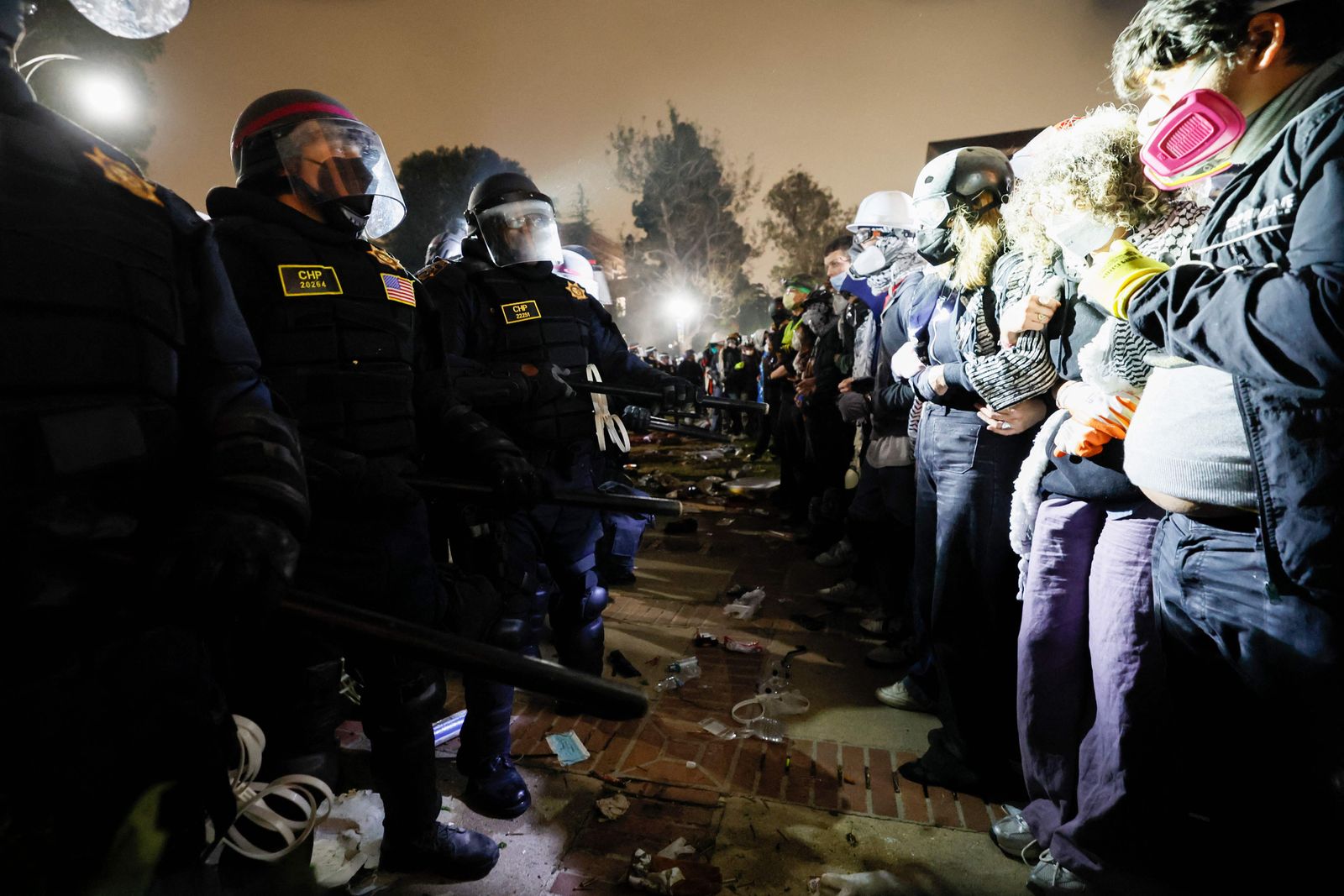 Police face-off with pro-Palestinian students after destroying part of the encampment barricade on the campus of the University of California, Los Angeles (UCLA) in Los Angeles, California, early on May 2, 2024. Police deployed a heavy presence on US university campuses on May 1 after forcibly clearing away some weeks-long protests against Israel's war with Hamas. Dozens of police cars patrolled at the University of California, Los Angeles campus in response to violent clashes overnight when counter-protesters attacked an encampment of pro-Palestinian students. (Photo by Etienne LAURENT / AFP)