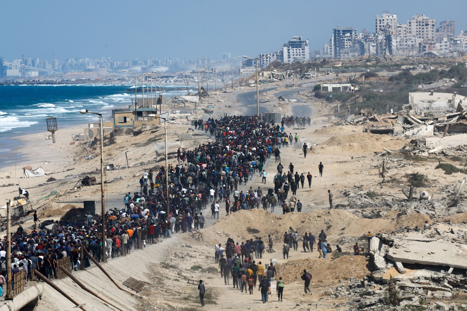 Palestinians, who were displaced to the southern part of Gaza at Israel's order during the war, walk along a road as they attempt to return to the north after a ceasefire between Israel and Hamas in Gaza went into effect, in the central Gaza Strip, October 10, 2025. REUTERS/Mahmoud Issa