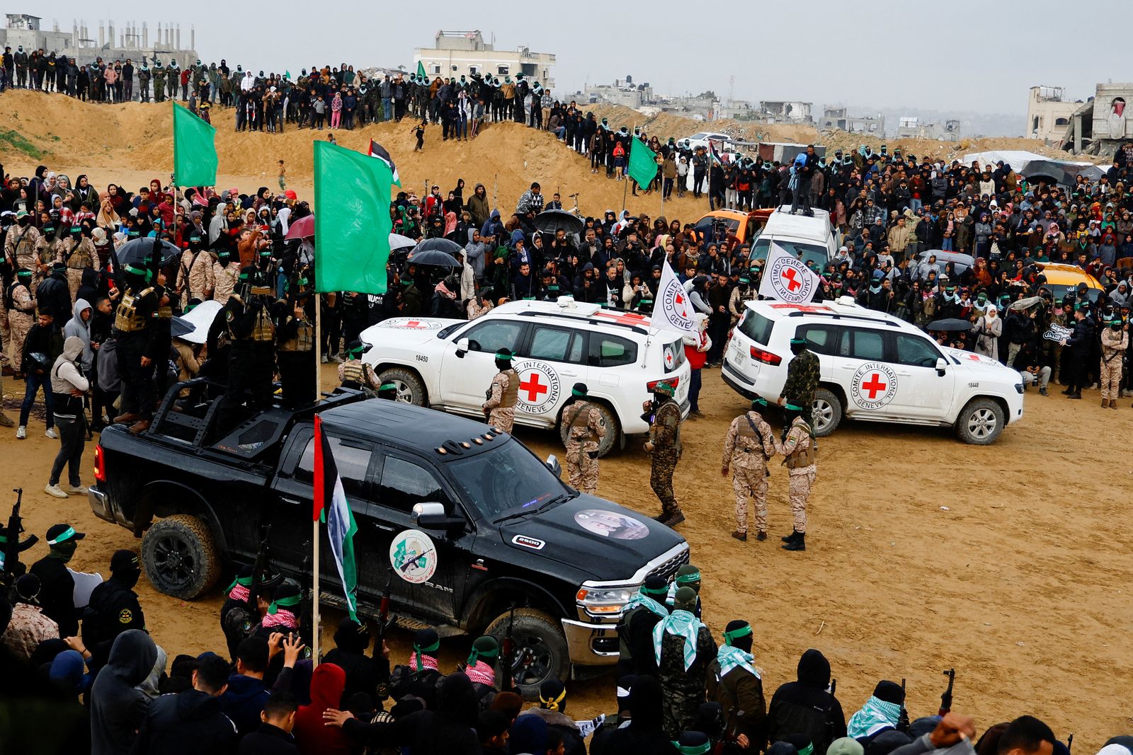 Palestinian militants and members of the Red Cross gather near vehicles on the day Hamas hands over deceased hostages Oded Lifschitz, Shiri Bibas and her two children Kfir and Ariel Bibas, seized during the deadly October 7, 2023 attack, to the Red Cross, as part of a ceasefire and hostages-prisoners swap deal between Hamas and Israel, in Khan Younis in the southern Gaza Strip February 20, 2025. REUTERS/Hatem Khaled