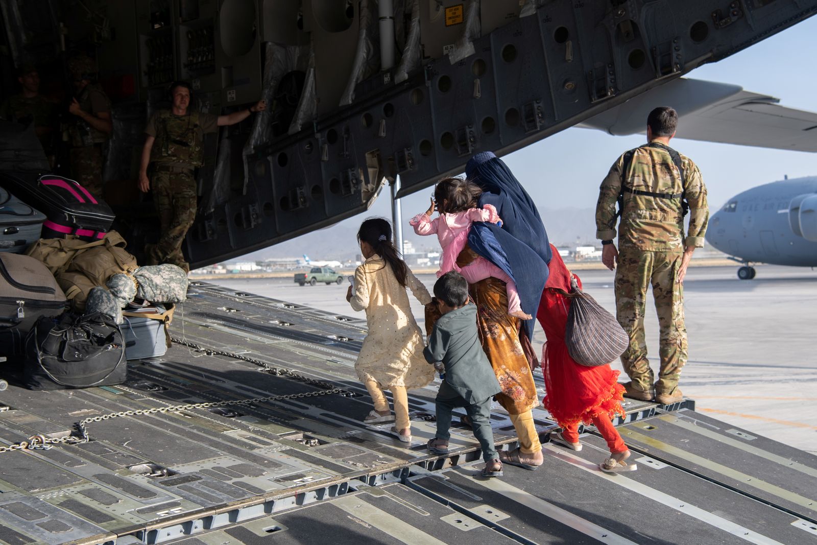 أفغانية وأطفالها يدخلون طائرة عسكرية أميركية لإجلائهم من مطار كابول - 24 أغسطس 2021 - REUTERS