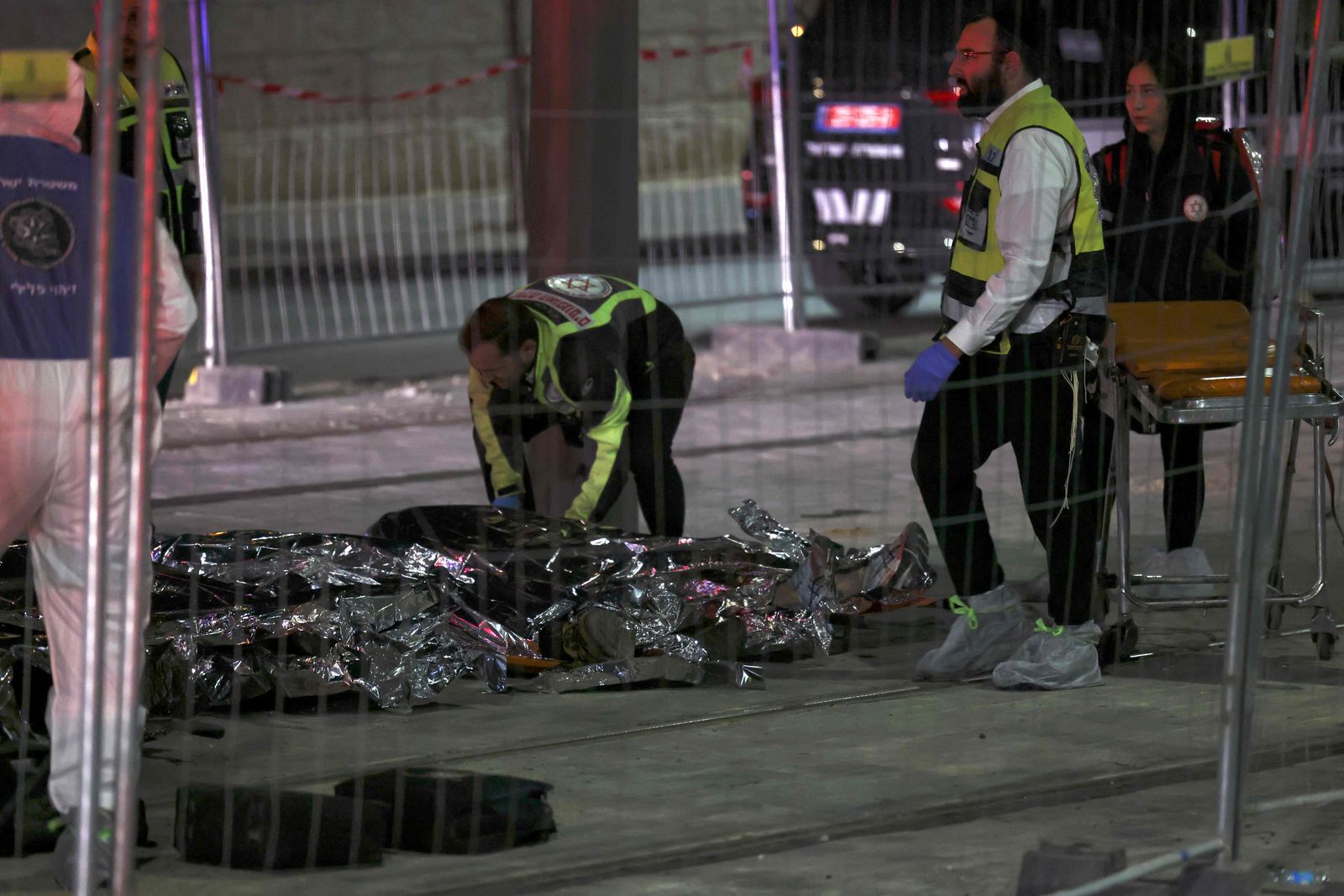 EDITORS NOTE: Graphic content / Israeli emergency service personnel work near casualties at the site of a reported attack in a settler neighbourhood of Israeli-annexed east Jerusalem, on January 27, 2023. (Photo by RONALDO SCHEMIDT / AFP) - AFP