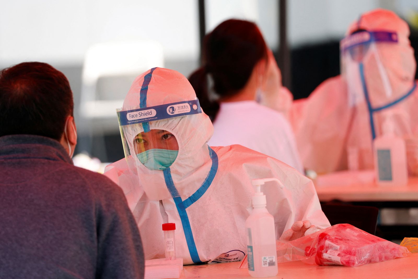 عمال طبيون يرتدون بدلات واقية يجمعون مسحات أنفية لكشف فيروس كورونا من السكان في منطقة هايديان ببكين. الصين 2 مايو 2022.  - REUTERS