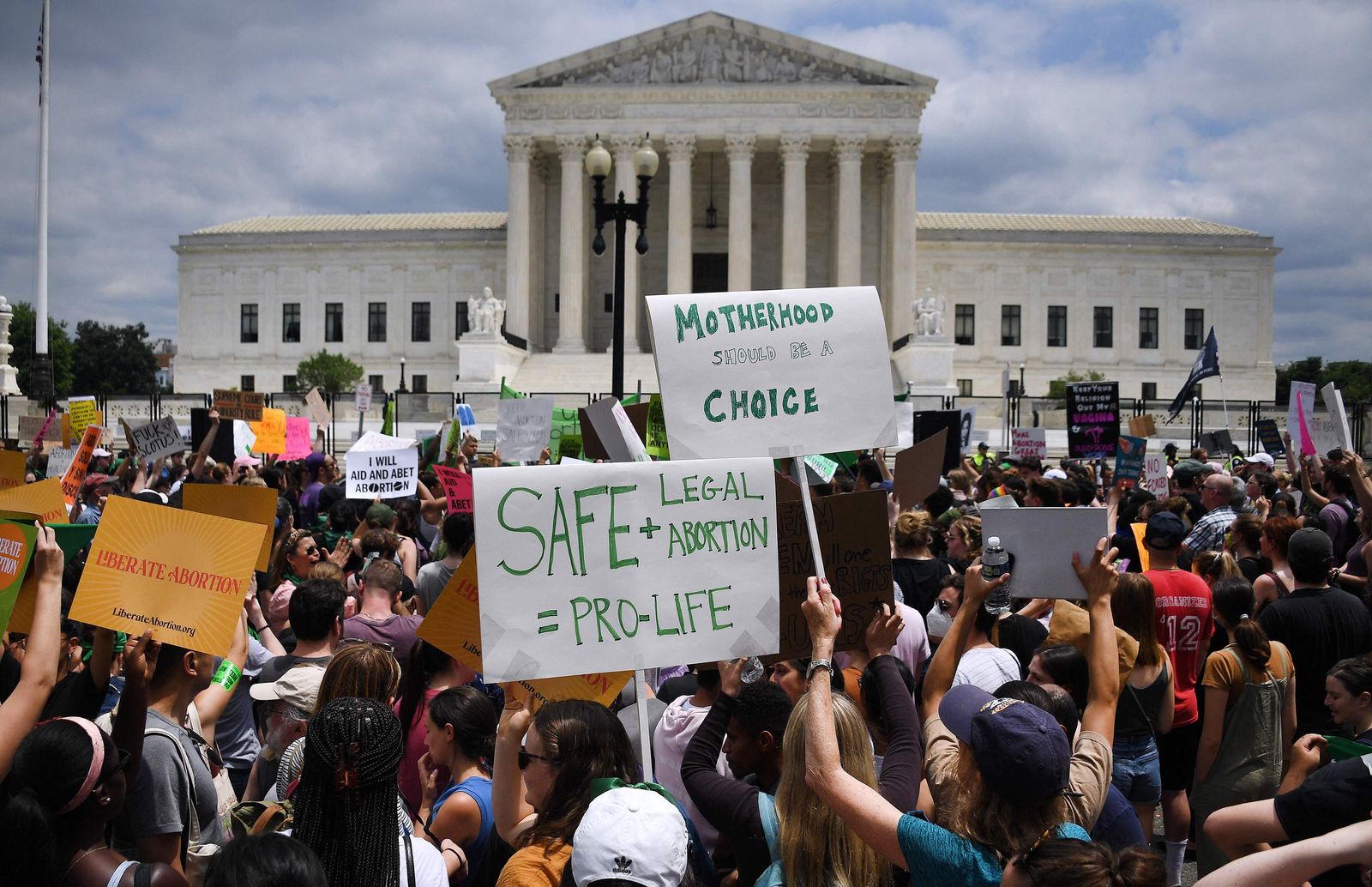 Abortion rights activists hoist their signs outside the US Supreme Court in Washington, DC, on June 24, 2022. - The US Supreme Court on Friday ended the right to abortion in a seismic ruling that shreds half a century of constitutional protections on one of the most divisive and bitterly fought issues in American political life. The conservative-dominated court overturned the landmark 1973 