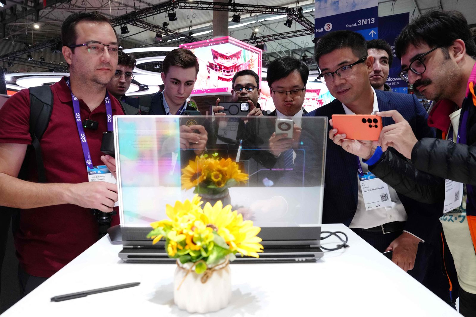 Visitors take picture of the new Lenovo ThinkBook laptop with a transparent display on the first day of the Mobile World Congress (MWC), the telecom industry's biggest annual gathering, in Barcelona on February 26, 2024. The world's biggest mobile phone fair throws open its doors in Barcelona with the sector looking to artificial intelligence to try and reverse declining sales. (Photo by PAU BARRENA / AFP)