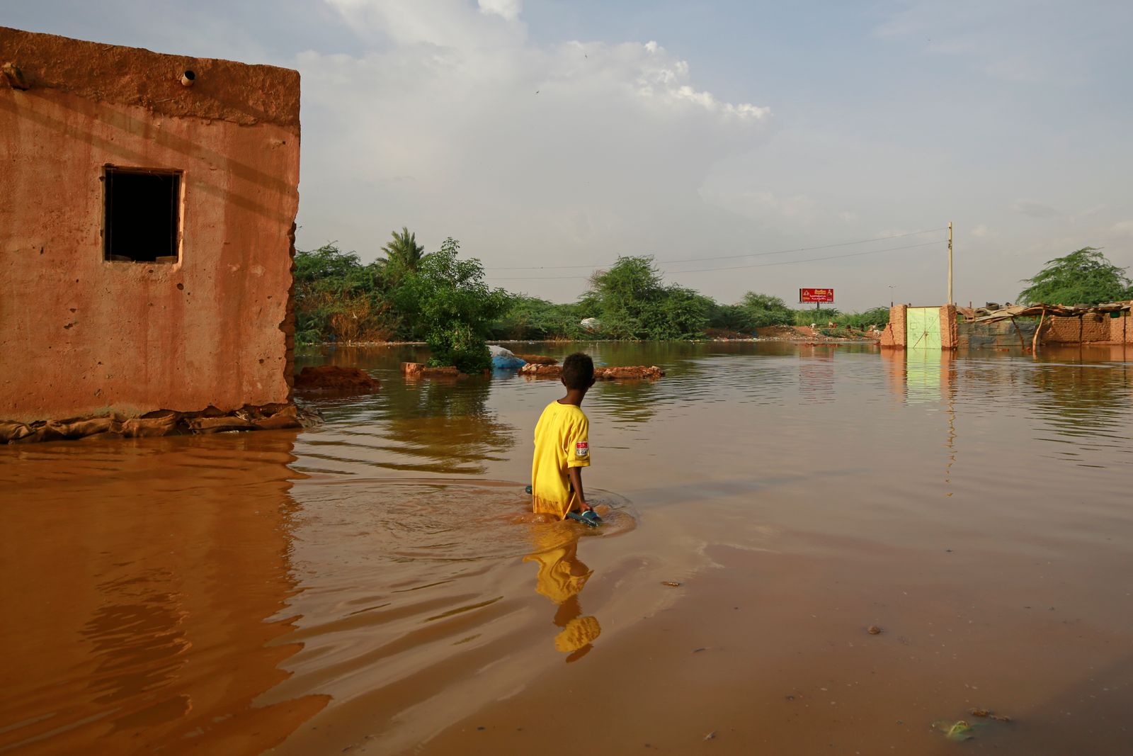 فتى سوداني يحاول اجتياز  شارع غمرته المياه في منطقة القماير في ولاية أم درمان في 26 أغسطس 2020 - AFP