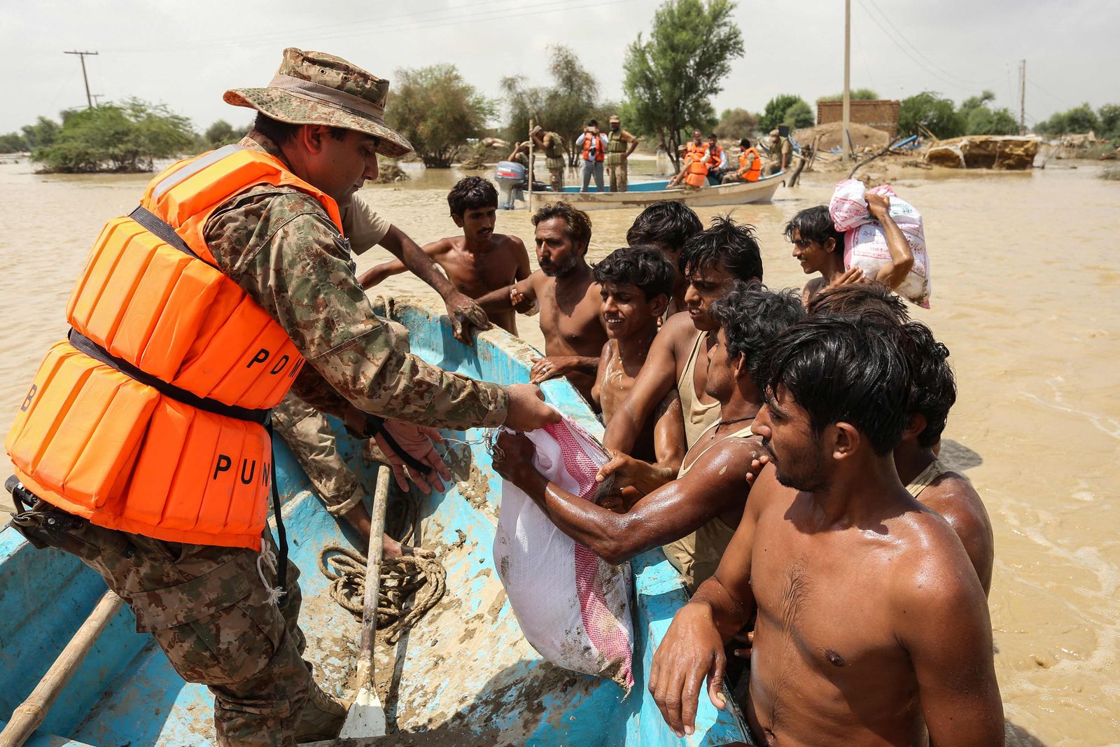 أفراد من الجيش الباكستاني يوزعون طرود غذائية على المتضررين من الفيضانات في منطقة راجانبور بإقليم البنجاب- 27 أغسطس 2022 - AFP