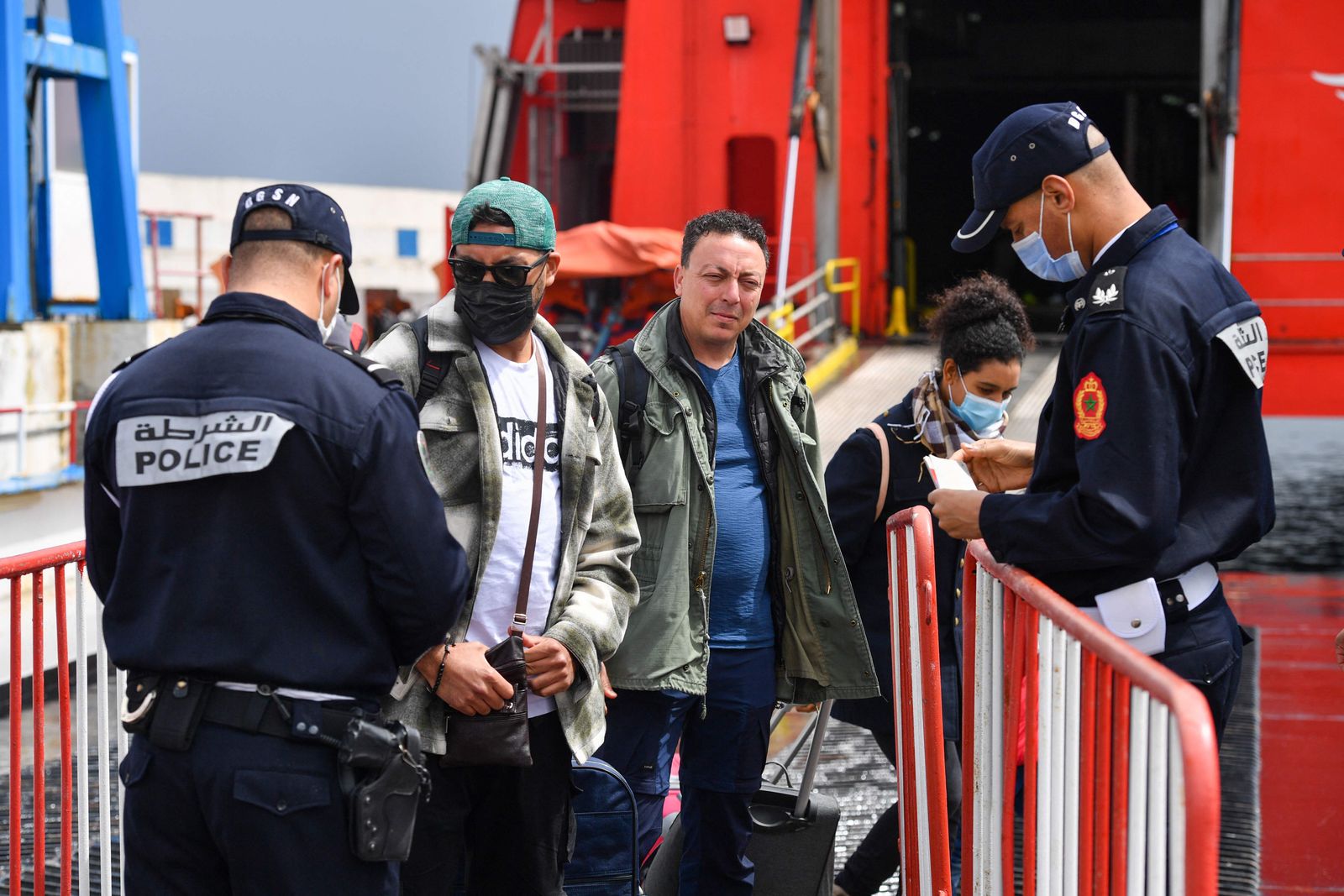 Policemen check IDs as people disembark from a ship coming from Spain at the Moroccan port of Tangiers on April 12, 2022 after the decision by Rabat and Madrid to open shipping lines between the two countries. - Maritime traffic between Spain and Morocco resumed following the normalisation of diplomatic relations between the two countries, Rabat's transport ministry said. (Photo by AFP) - AFP