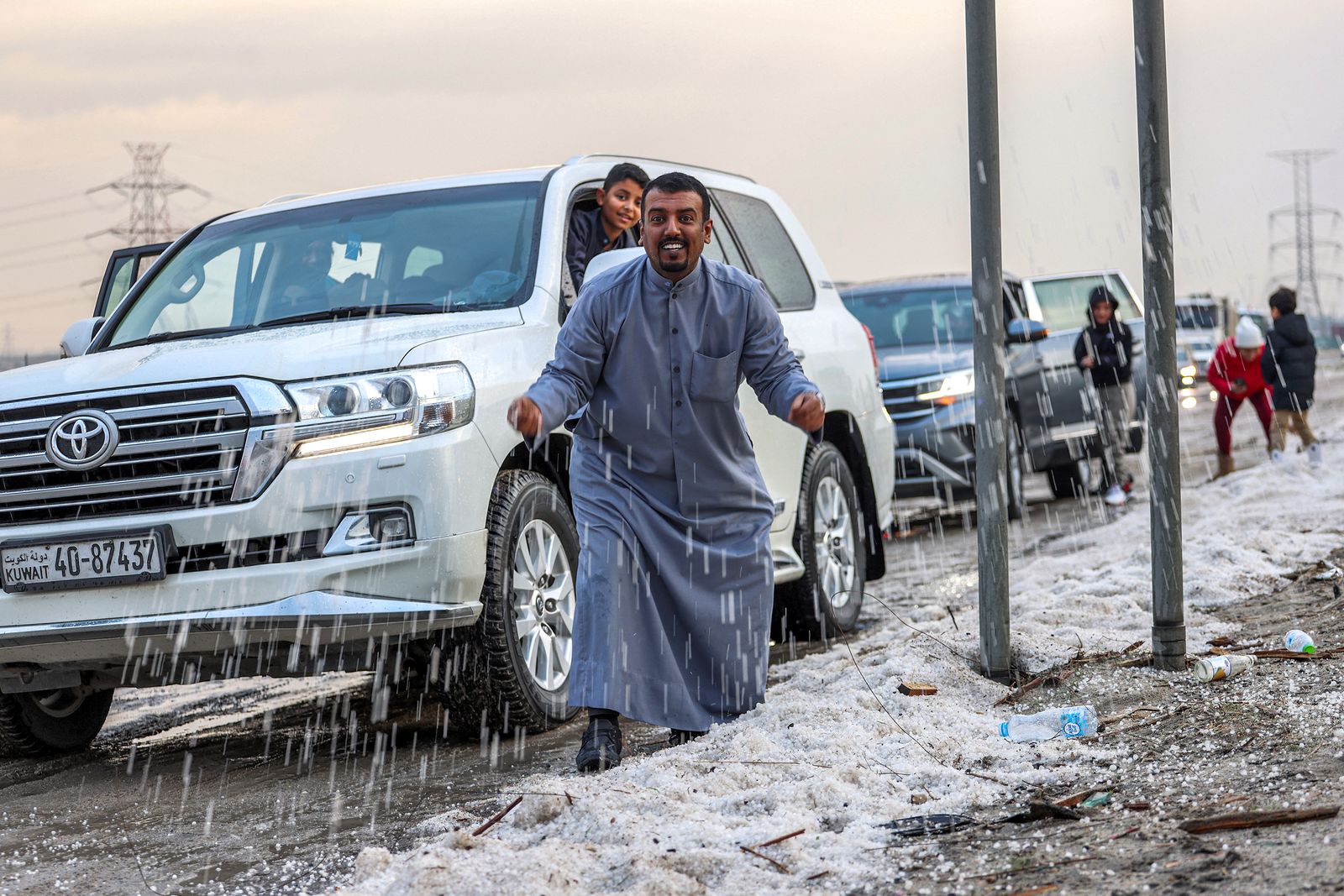 أشخاص يعبرون عن مشاعرهم مع تساقط زخات البرد في منطقة أم الهيمان جنوب العاصمة الكويت - 27 ديسمبر 2022 - AFP