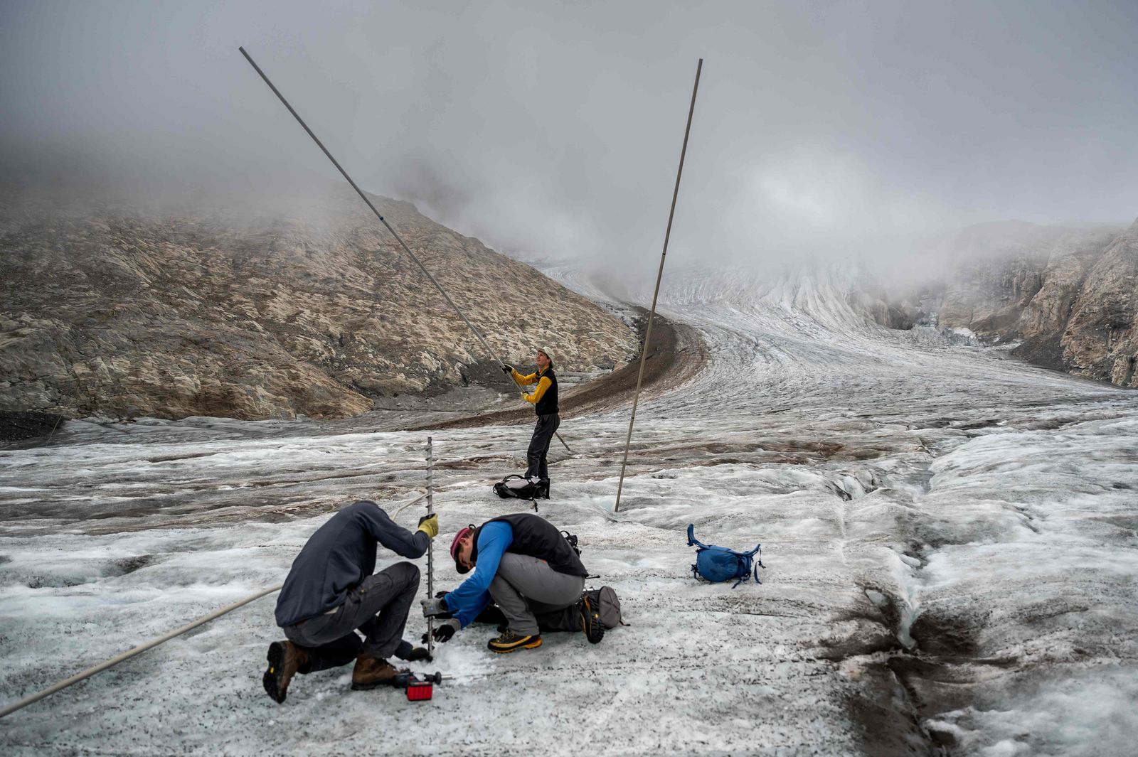 This picture taken on September 2, 2022 above Ulrichen shows glaciologist and head of 'Glacier Monitoring in Switzerland' (GLAMOS) network Matthias Huss (with yellow shirt) during a visit with his team on the Gries glacier to takes readings of measuring equipments. - Swiss glaciers smashed all records for melting in 2022, under the dual effect of a dry winter and a long wave of intense summer heat. Three cubic kilometres of ice - three thousand billion litres of water - literally evaporated, or 6% of the total volume of Swiss glaciers, according to a report by the (GLAMOS) network published on September 28, 2022. (Photo by Fabrice COFFRINI / AFP) - AFP