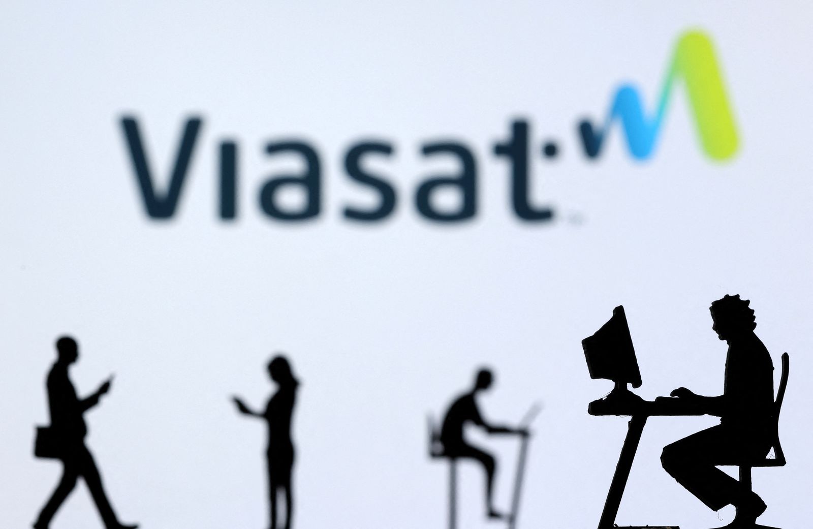 FILE PHOTO: Illustration shows small toy figures with laptops and smartphones in front of displayed Viasat Internet logo - REUTERS