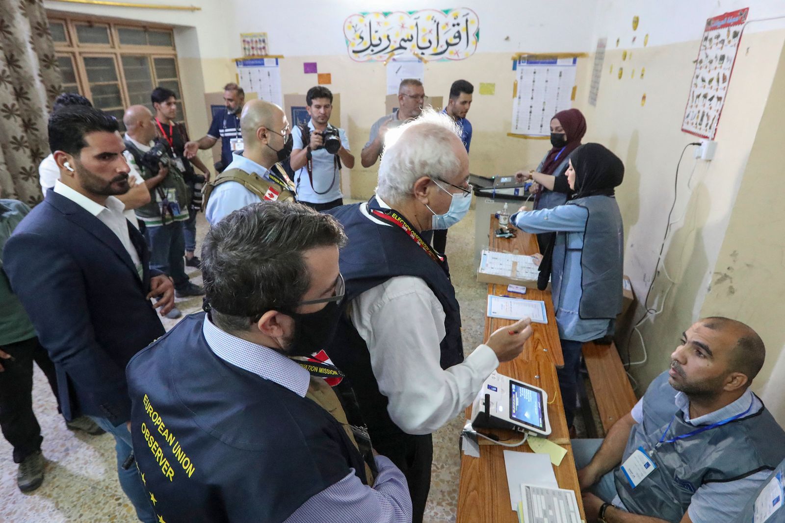 مراقبو الاتحاد الأوروبي يتحدثون مع مسؤولي الانتخابات العراقيين أثناء فرز إلكتروني للأصوات في مركز اقتراع بالعاصمة بغداد – وكالة الأنباء الفرنسية. - AFP