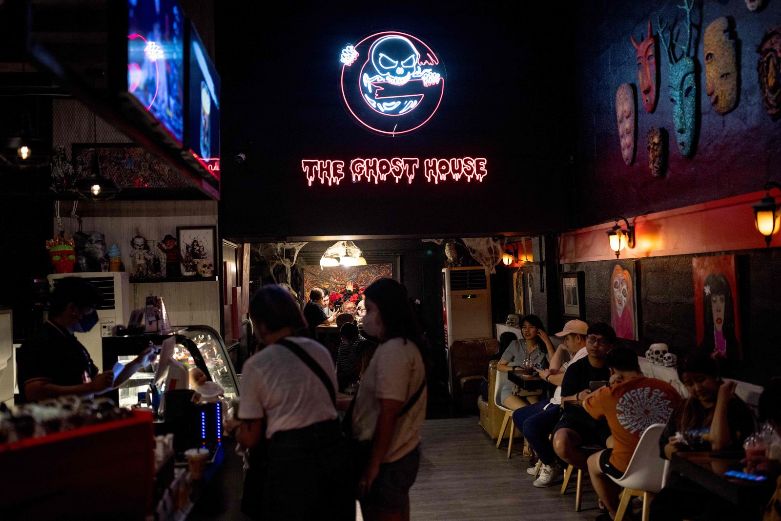 In this photo taken on March 25, 2023 guests listen to the live show of Ghost Radio station host Jack Watcharaphonat at his Ghost House cafe in Bangkok. - It is almost midnight, and above a semi-abandoned Bangkok shopping centre, Ghost Radio is on air. Rapid-fire comments ping across the studio's screens as thousands tune in online to hear callers describe their encounters with Thailand's supernatural. (Photo by Jack TAYLOR / AFP) / To go with 'THAILAND-RELIGION-CULTURE-PEOPLE,FOCUS' by Thanaporn PROMYAMYAI and Rose TROUP BUCHANAN - AFP