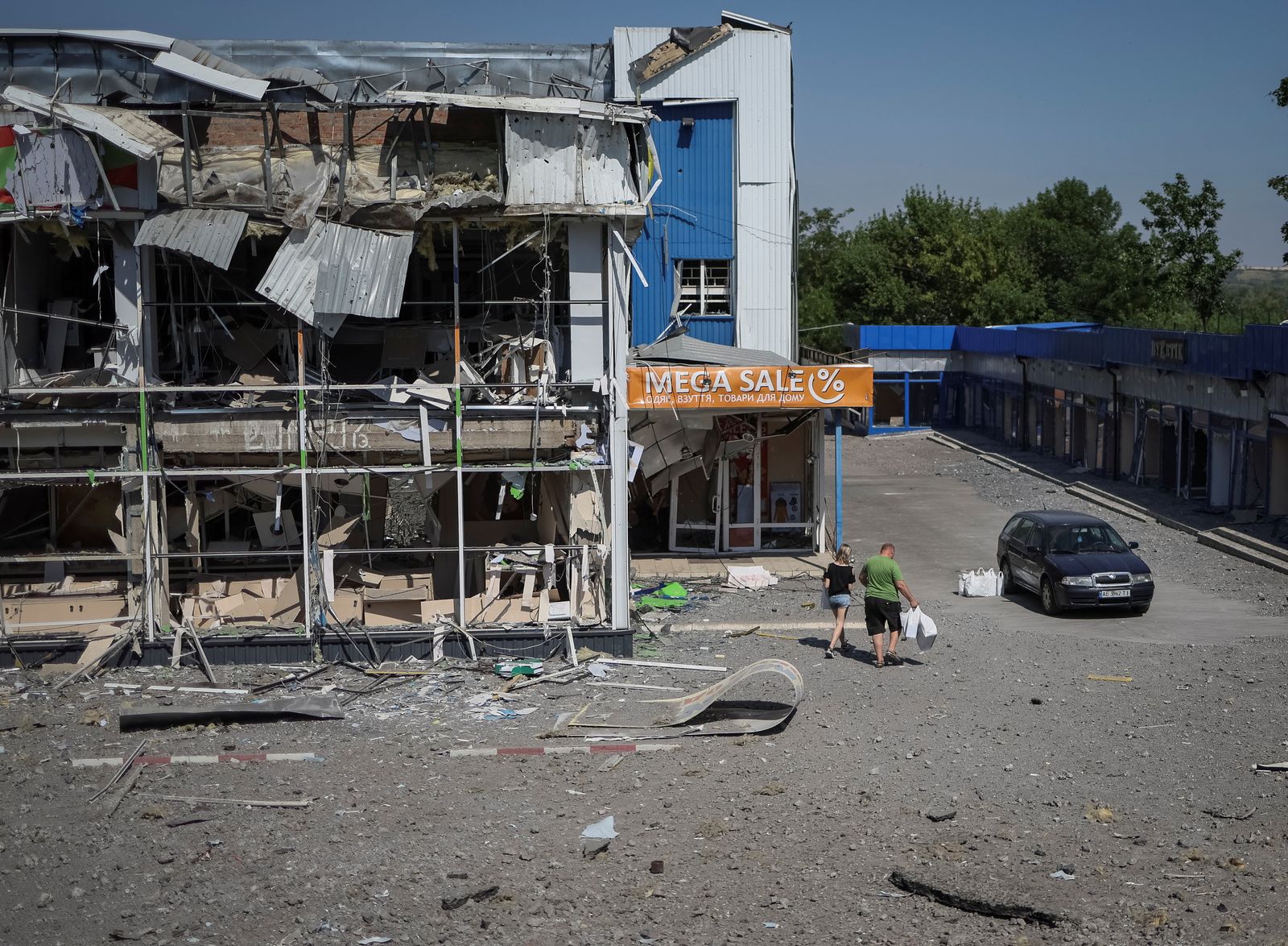 عدد من سكان منطقة دونيتسك يسرون بجانب مركز تسوق دمرته ضربة عسكرية روسية - 9 يوليو 2022 - REUTERS