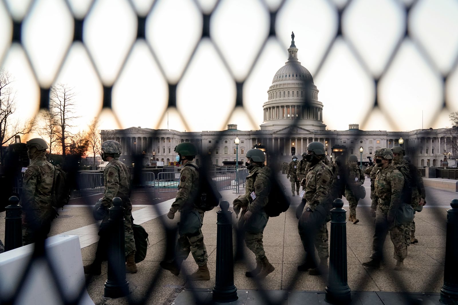 مجموعة من الحرس الوطني الأميركي تمر أمام السياج التي يتحصن بها مبنى الكابتيول - REUTERS