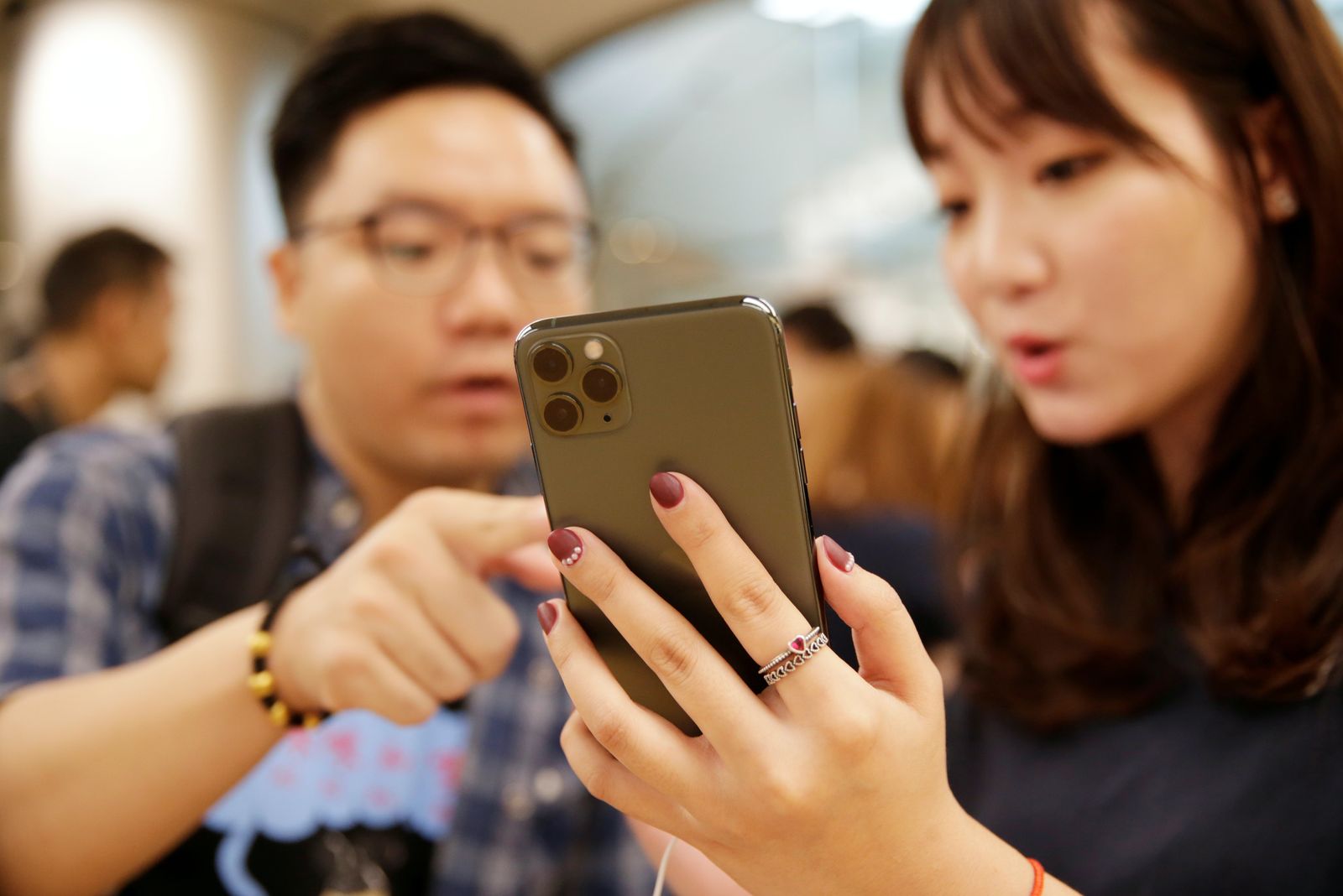 مستخدمون صينيون يحملون جهاز آيفون برو ماكس 11 في أحد متاجر آبل بالعاصمة بكين 20 سبتمبر 2019 - REUTERS