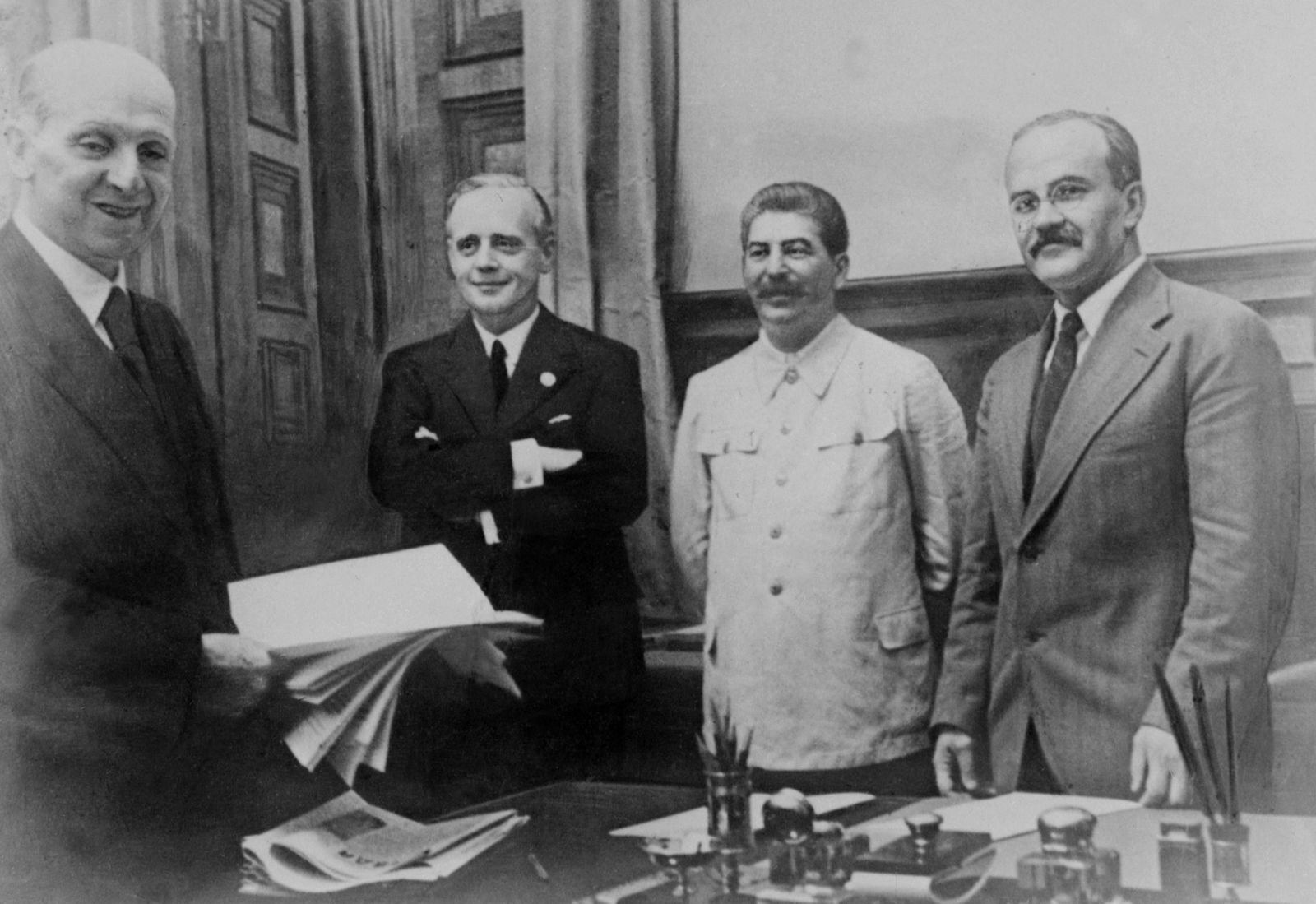 الزعيم السوفياتي جوزيف ستالين متوسطاً وزير الخارجية الألماني يواخيم فون ريبنتروب (إلى يمينه) ووزير الخارجية السوفياتي فياتشيسلاف مولوتوف بعد توقيع الاتفاق بين الجانبين في الكرملين - 23 أغسطس 1939 - AFP
