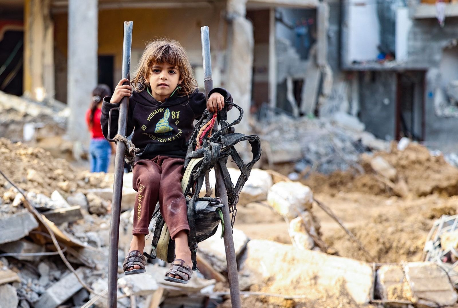 فتاة فلسطينية تجلس وسط الأنقاض في حيّها الذي تعرض للقصف الإسرائيلي في غزة - 21 مايو 2021 - AFP