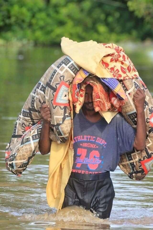 شاب سوداني يحمل فراش النوم في وسط المياه - فيسبوك
