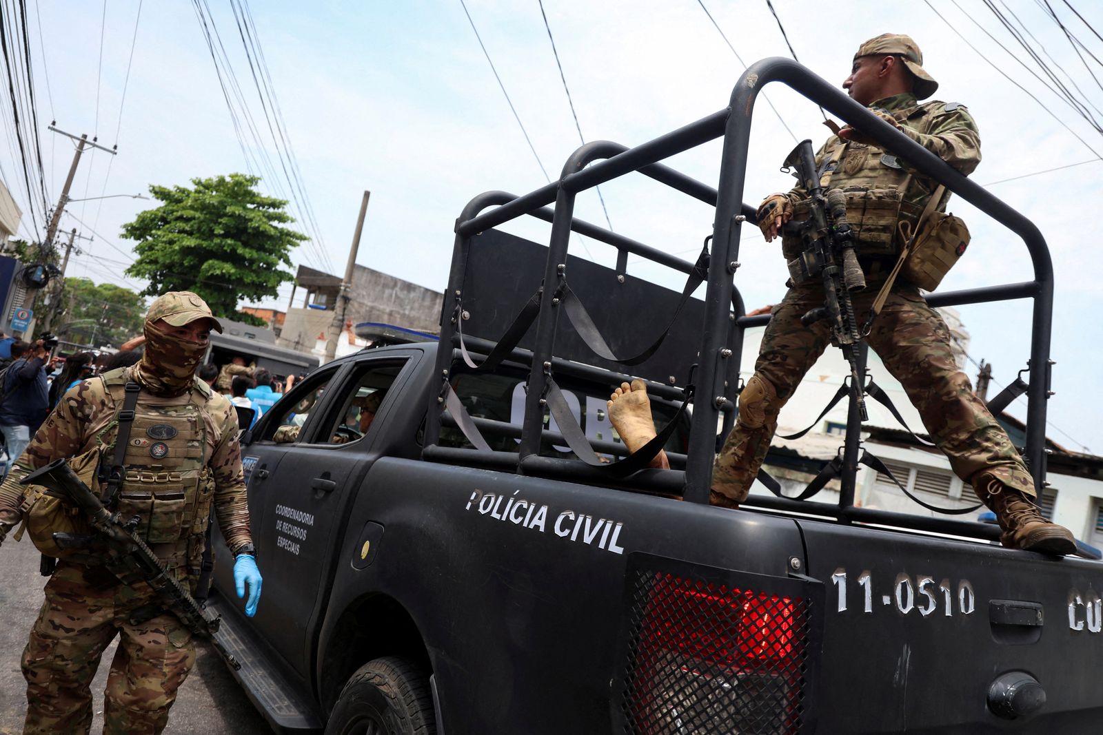 SENSITIVE MATERIAL. THIS IMAGE MAY OFFEND OR DISTURB    A member of the tactical police unit stands in the back of a vehicle while transporting a dead body during a police operation against drug trafficking at the favela do Penha, in Rio de Janeiro, Brazil, October 28, 2025. REUTERS/Aline Massuca