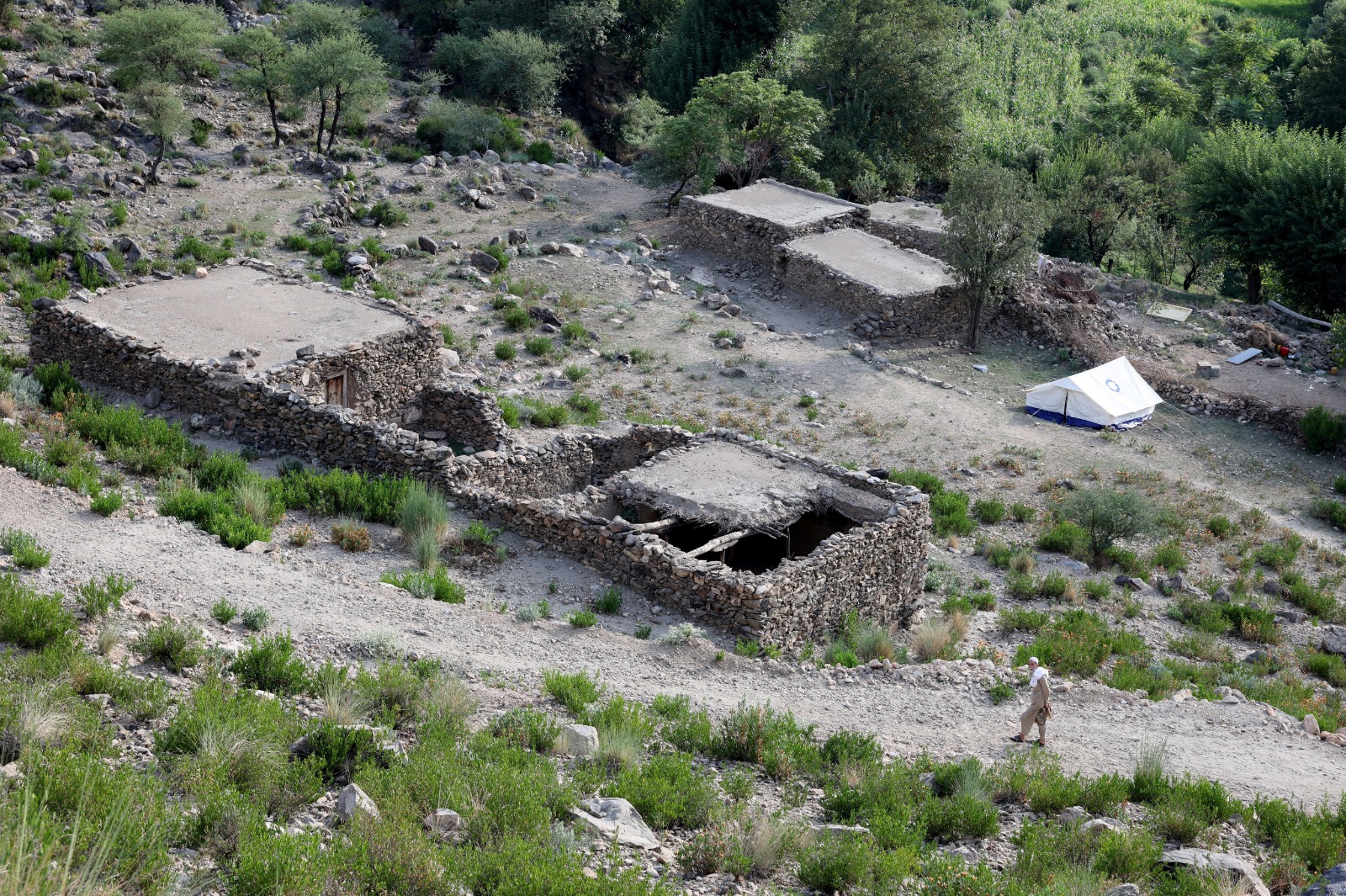 رجل أفغاني يسير بجوار منزل متضرر عقب الزلزال المميت الذي ضرب ولايتي كونار وننكرهار في أفغانستان، في منطقة نورغال بولاية كونار، 4 سبتمبر 2025
