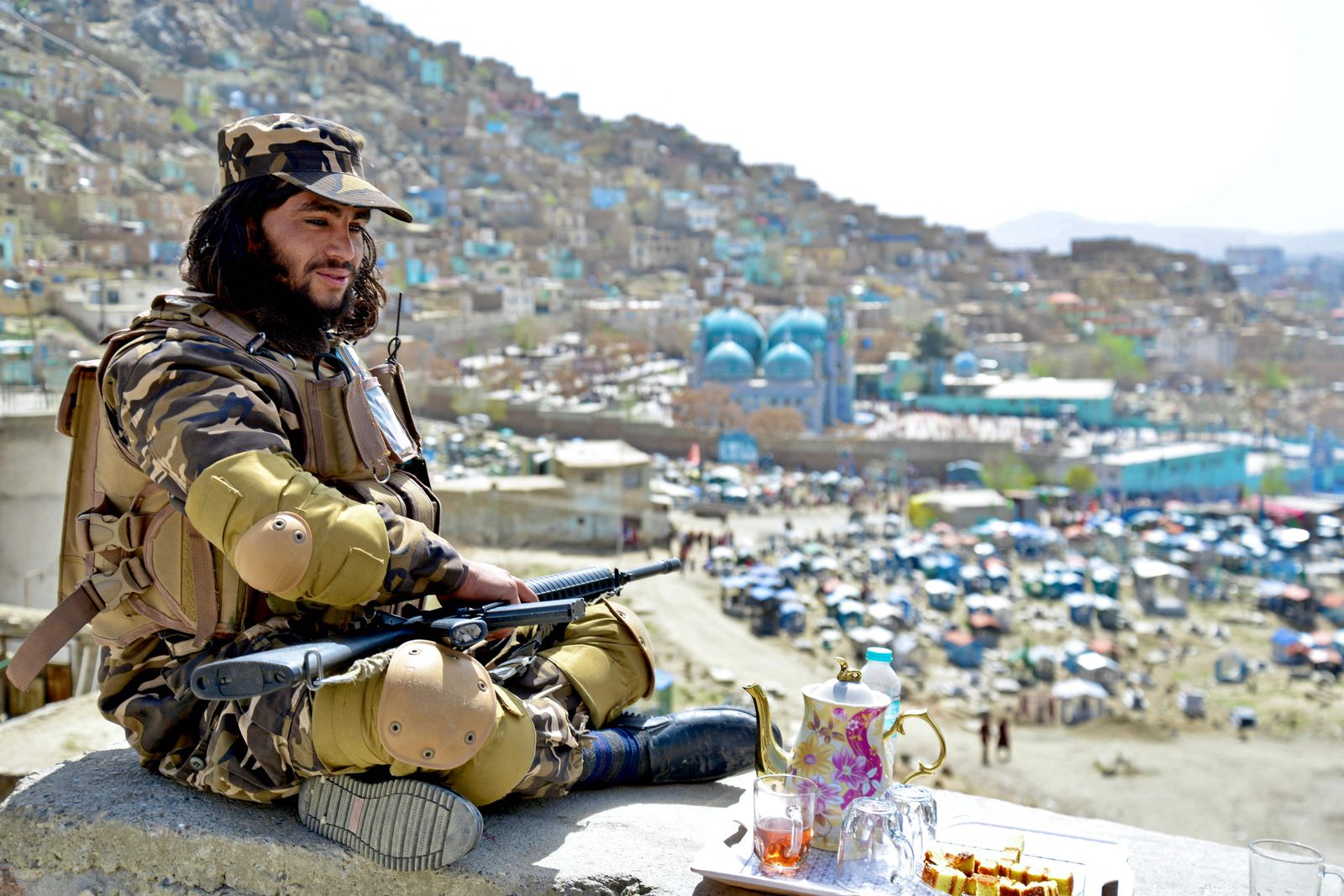 A Taliban fighter sits against the backdrop of Karte Sakhi shrine on the first day of 'Nowruz' marking the Persian New Year in Kabul on March 21, 2022. (Photo by Ahmad SAHEL ARMAN / AFP) - AFP