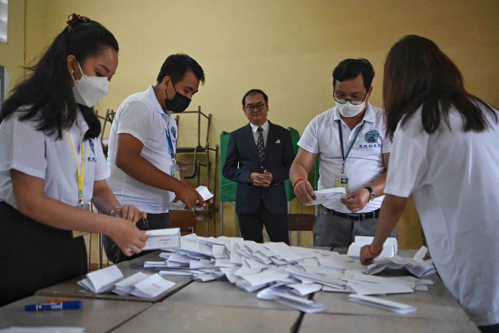 Cambodian election officials count ballots as Sovannarom Dim (C), a member of the National Election Committee and chief of quick reaction information team of NEC, observes at a polling station during local commune elections in Phnom Penh on June 5, 2022. (Photo by TANG CHHIN Sothy / AFP) - AFP