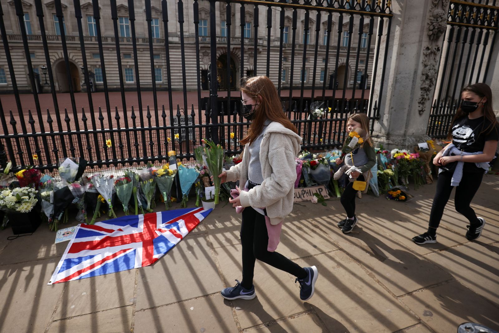 أطفال يضعون الزهور أمام قصر باكنغهام الملكي وسط لندن بعد الإعلان عن وفاة دوق أدنبرة الأمير فيليب- 9 أبريل 2021 - REUTERS