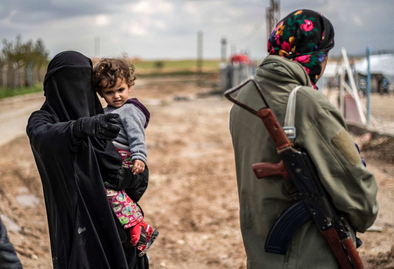 محتجزة أجنبية في مخيم الهول شمالي سوريا تحمل طفلتها، وتتحدث إلى أحد عناصر قوات سوريا الديمقراطية (قسد) التي تدير المخيم- 28 مارس 2019 - AFP