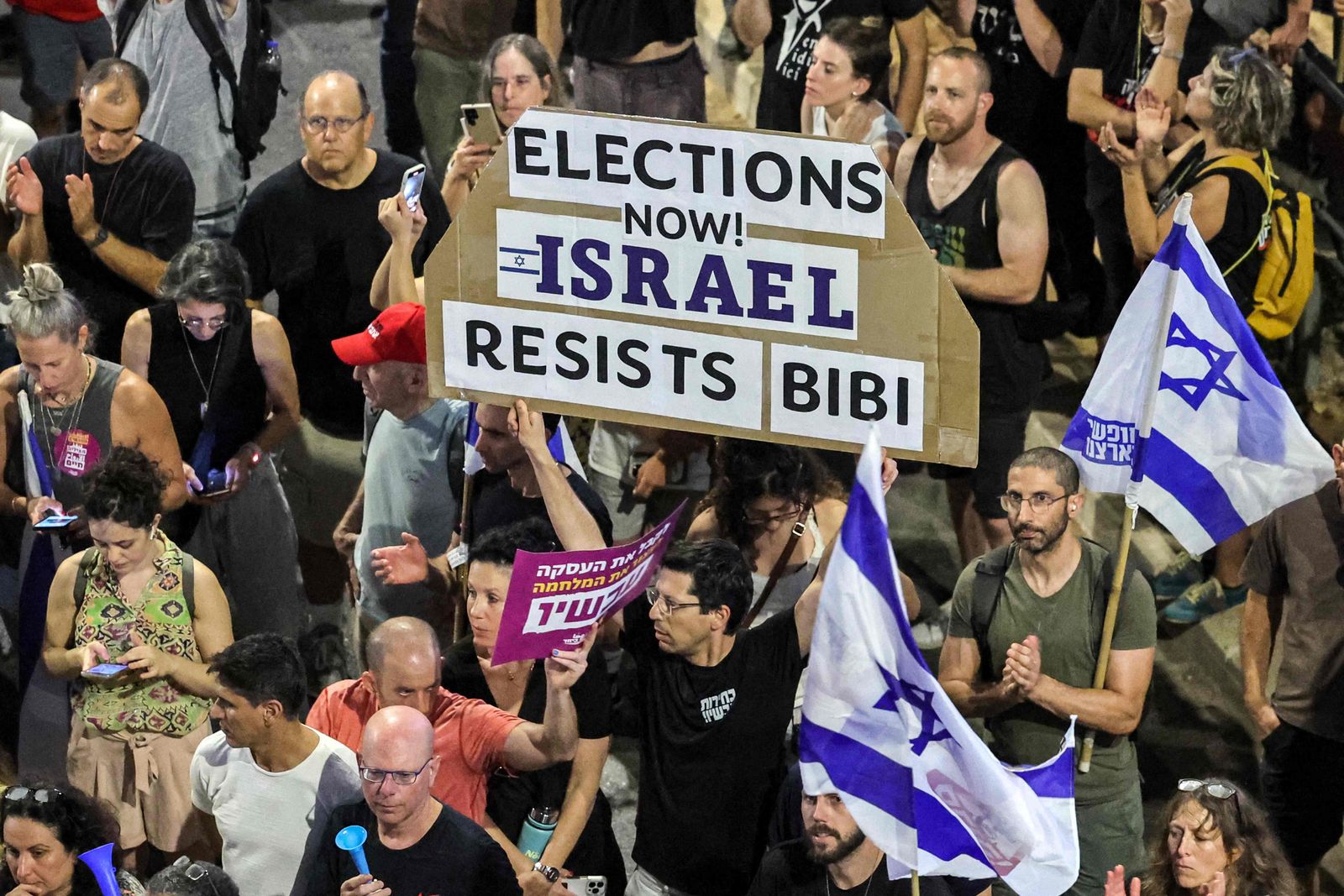 Protesters gather with signs during an anti-government demonstration in Tel Aviv on June 15, 2024, calling for early elections, the return of the hostages held captive in the Gaza Strip since the October 7 attacks, and an end to the ongoing conflict in the Palestinian territory between Israel and Hamas. (Photo by JACK GUEZ / AFP)