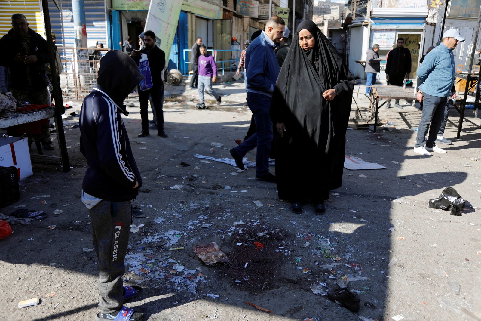  أشخاص يتفقدون موقع الدمار في أعقاب هجوم انتحاري مزدوج في سوق مركزي في بغداد 21-1-2021 - REUTERS