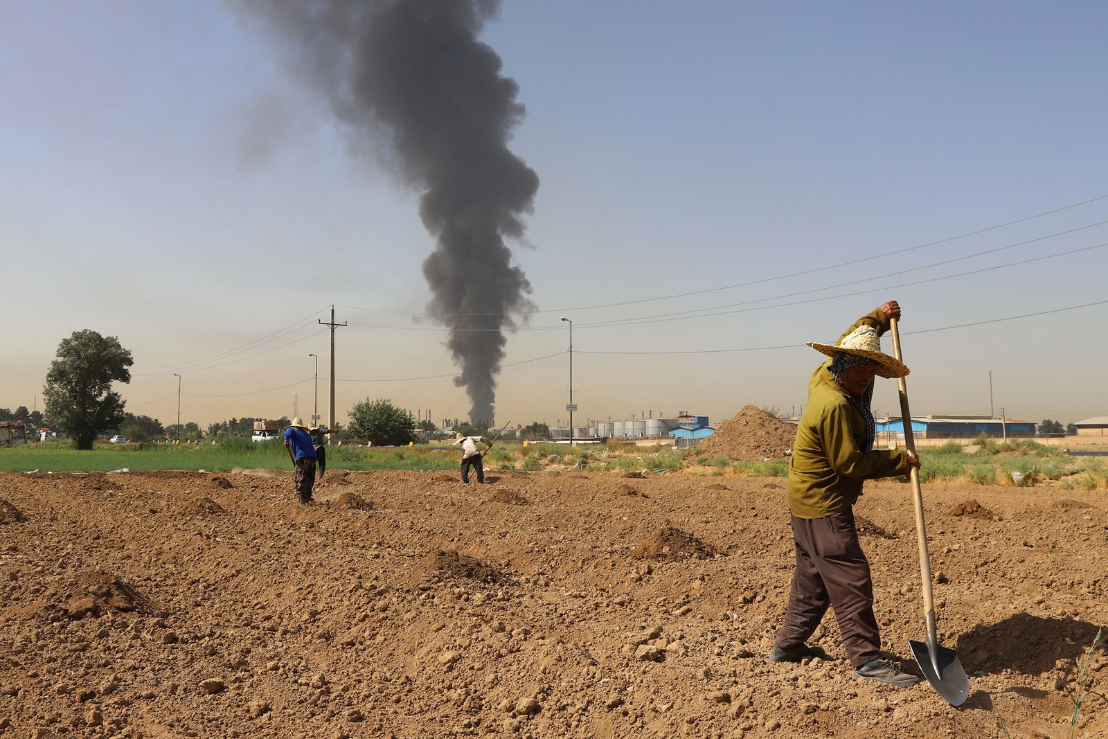عمود الدخان المتصاعد من حريق مصفاة النفط يمكن رؤيته من حقل زراعي يبعد كيلومترات- 3 يونيو 2021 - via REUTERS