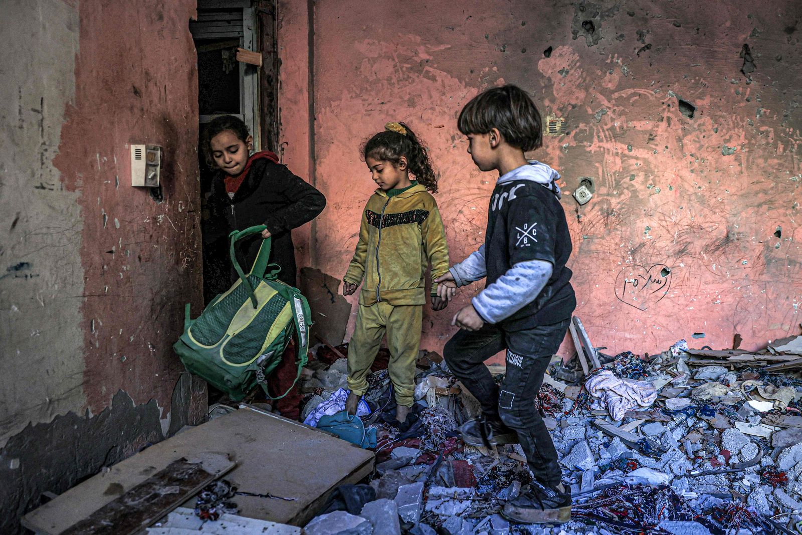 Children inspect items in the rubble in a room overlooking a buildingdestroyed by Israeli bombardment in Rafah in the southern Gaza Strip on December 24, 2023 amid the ongoing conflict between Israel and the militant group Hamas. (Photo by SAID KHATIB / AFP)