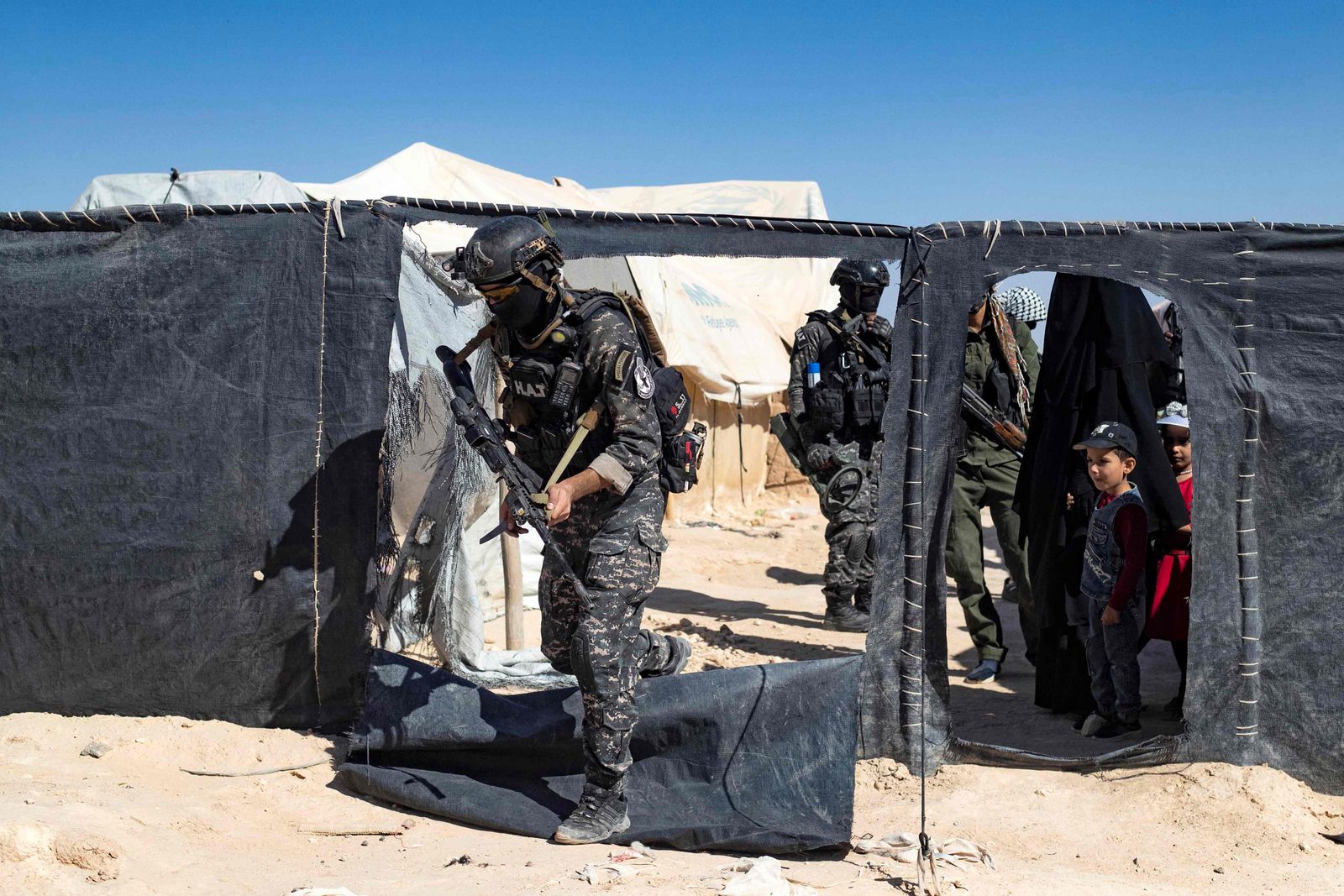 Members of the Syrian Kurdish Asayish security forces inspect tents at the Kurdish-run al-Hol camp, which holds relatives of suspected Islamic State (IS) group fighters in the northeastern Hasakeh governorate, on August 28, 2022, during a security campaign by the Syrian Democratic Forces against IS 'sleeper cells' in the camp. (Photo by Delil SOULEIMAN / AFP)