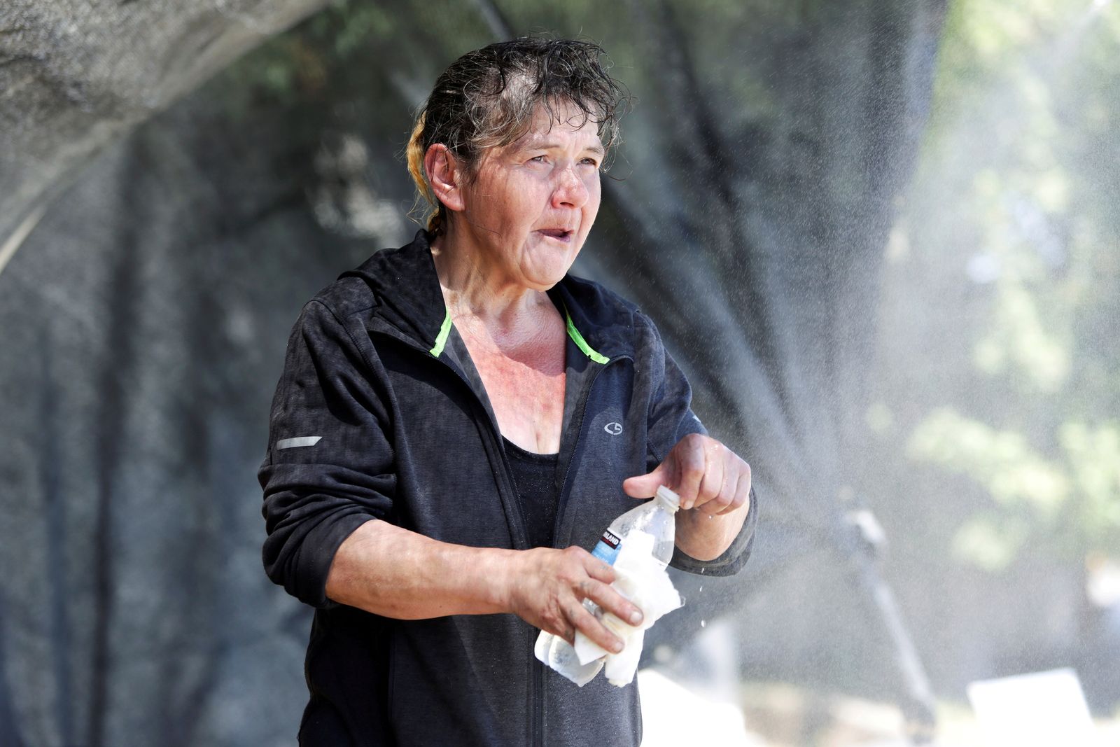 امرأة تشرب المياه وتبدو عليها آثار الارهاق من الحر . - REUTERS