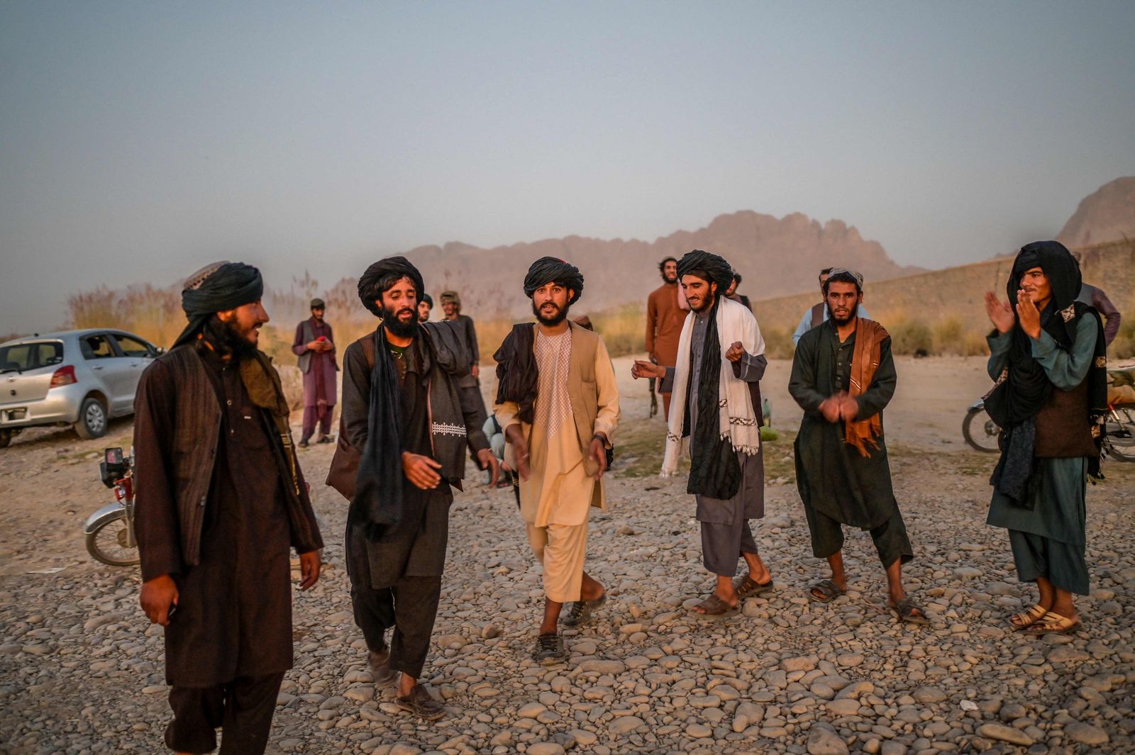 In this picture taken on September 23, 2021, Taliban members enjoy a traditional dance on the banks of a river in Kandahar. (Photo by Bulent KILIC / AFP) - AFP