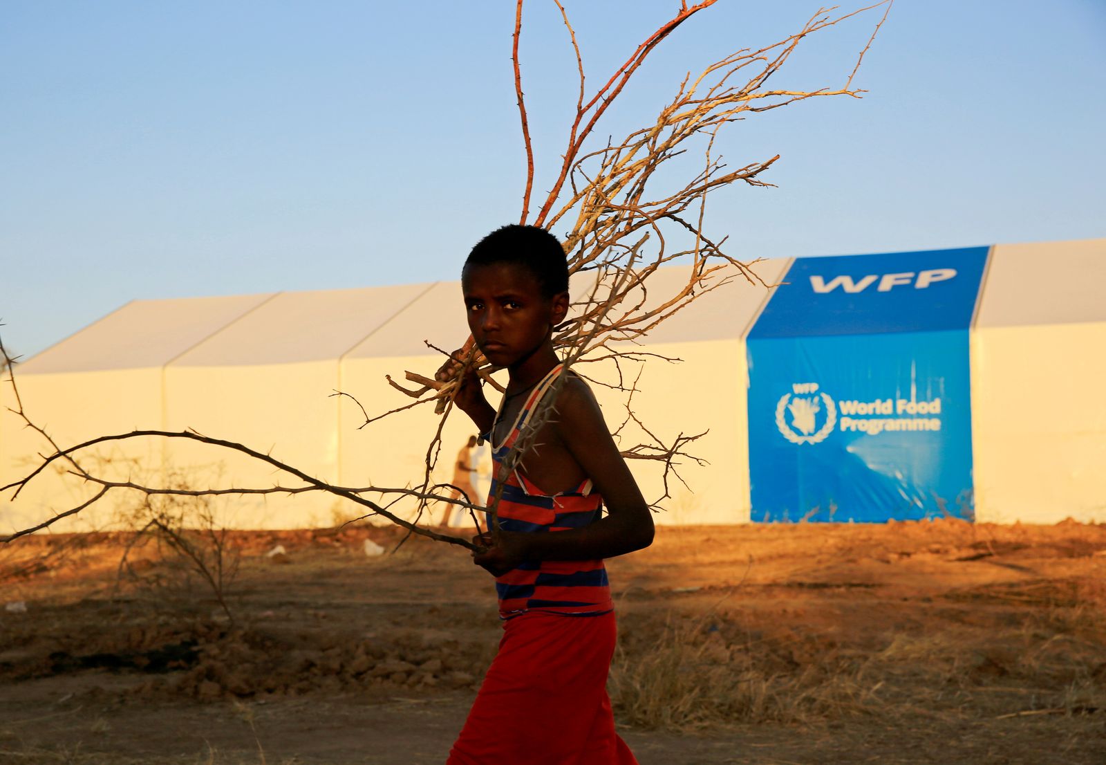 طفل إثيوبي يفر من القتال الدائر في منطقة تيغراي، يمر أمام خيمة برنامج الغذاء العالمي. - REUTERS