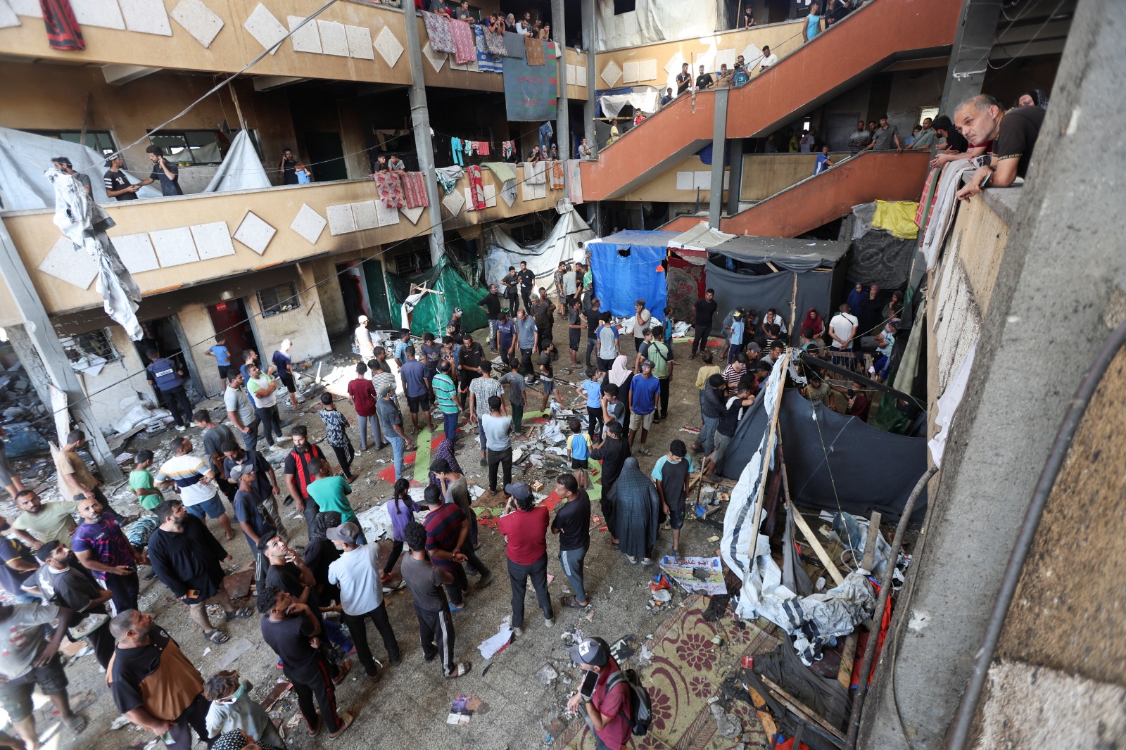 فلسطينيون يتفقدون موقع غارة إسرائيلية على مدرسة تؤوي نازحين في دير البلح وسط قطاع غزة في 10 أكتوبر 2024