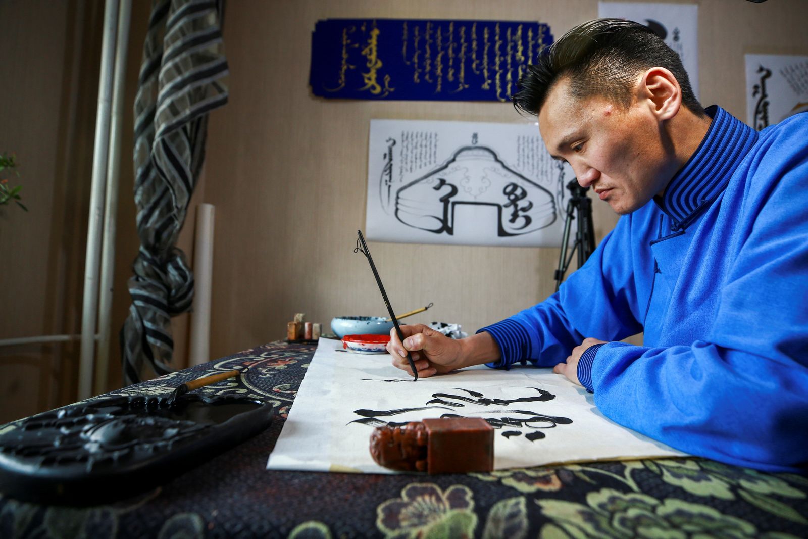 This photo taken on Novemver 3, 2020 shows calligrapher Ganzorig Gulguu, who earned money by selling his calligraphy art work mainly to Inner Mongolia, writing Mongolian scripts at his home in Ulaanbaatar, the capital of Mongolia. (Photo by Byambasuren BYAMBA-OCHIR / AFP) - AFP