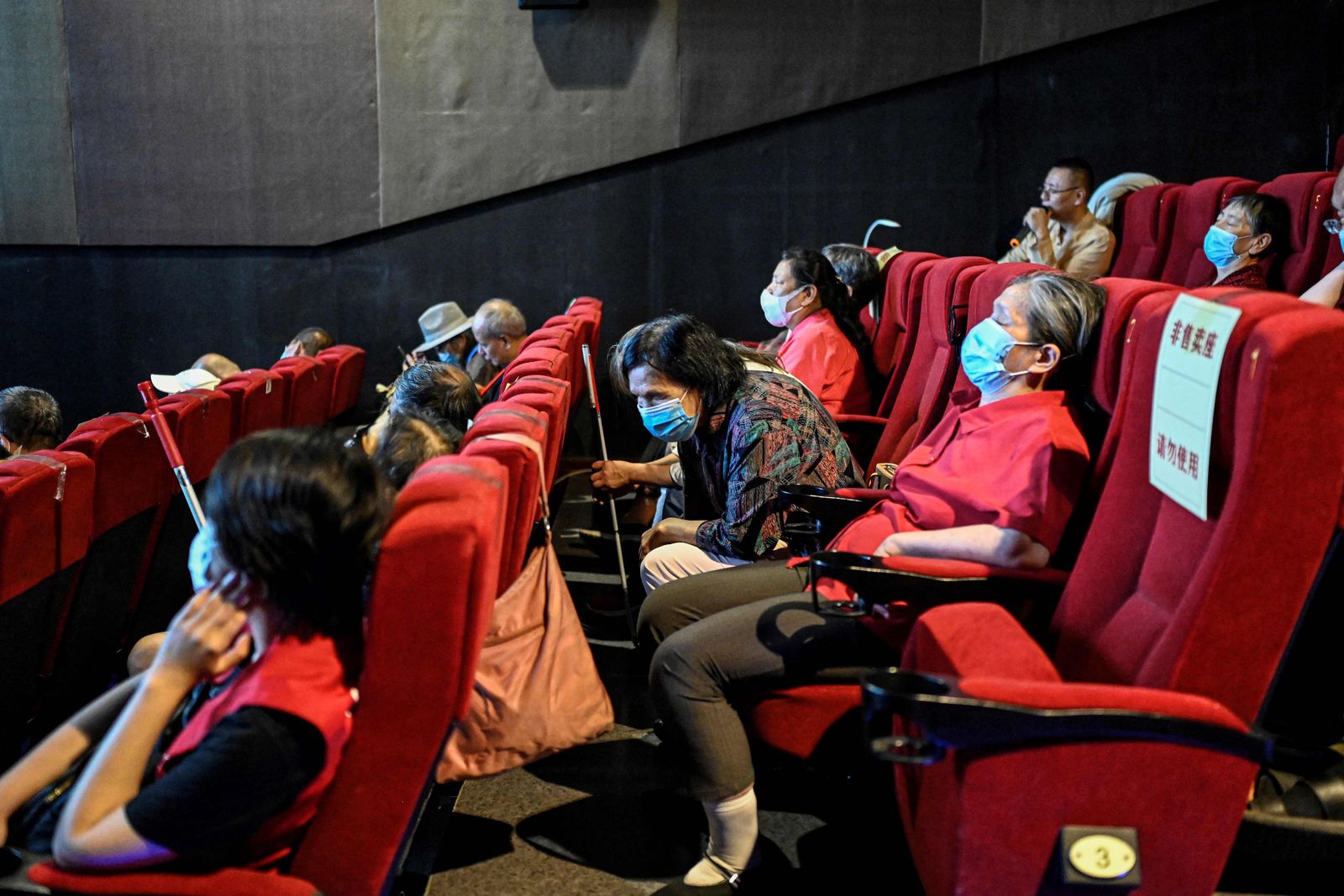This photo taken on August 7, 2021 shows visually impaired people listening to the film narrator during a screening at a cinema in Beijing. - Dozens of blind moviegoers come to the Saturday screenings organised by Xin Mu Theater, a small group of volunteers who were the first to introduce films to blind audiences in China. (Photo by Jade GAO / AFP) / To go with AFP story China-social-disabled-film, FEATURE by Poornima WEERASEKARA and Danni ZHU - AFP