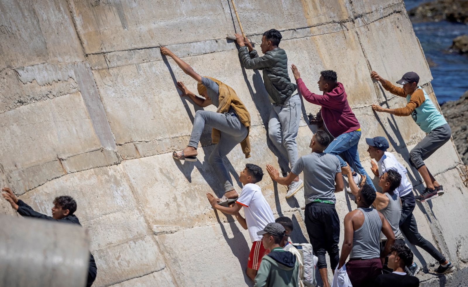 يتسلّقون جداراً بحرياً بعد محاولتهم عبور الحدود من المغرب إلى سبتة - 19 مايو 2021 - AFP