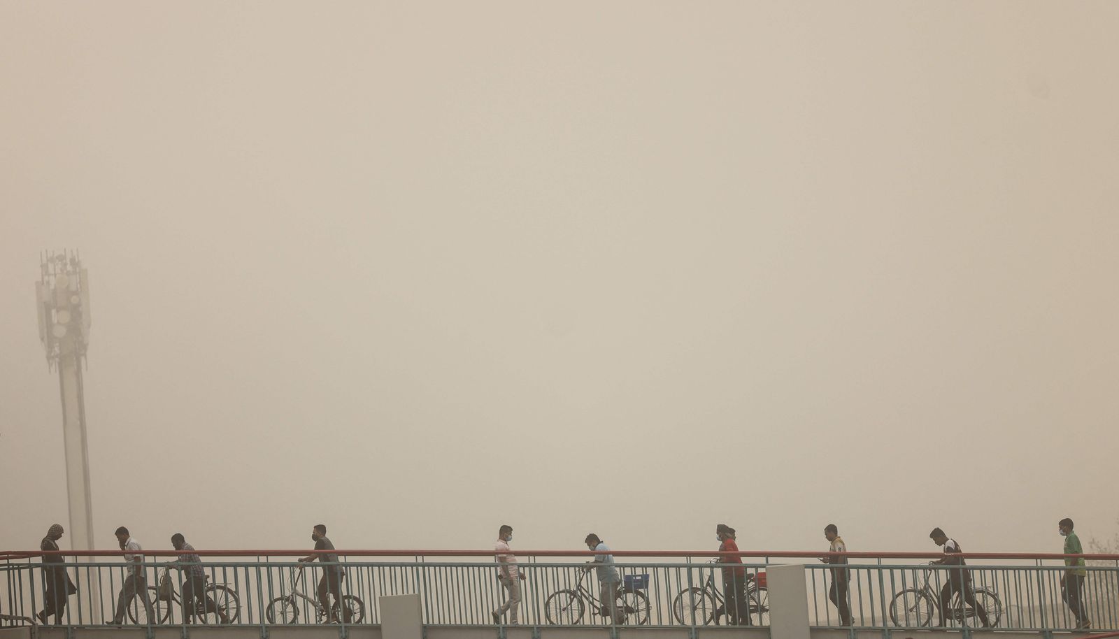 People walk across a bridge during a sand storm in the Gulf emirate of Dubai, on August 14, 2022. (Photo by Karim SAHIB / AFP) - AFP