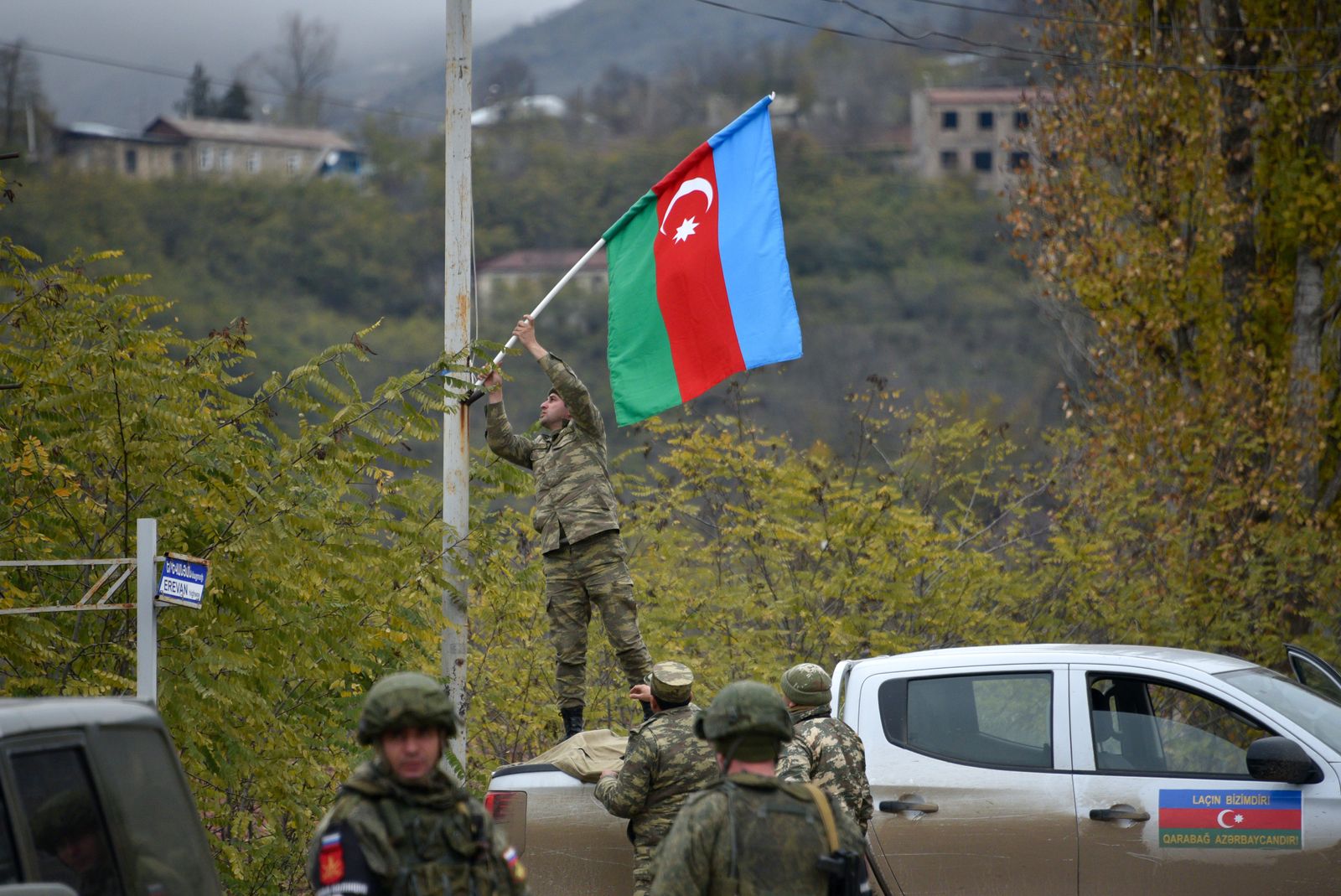 جندي أذربيجاني يثبت علم بلاده على عمود إنارة في بلدة لاتشين بعد دخولها في 1 ديسمبر 2020 بموجب اتفاق السلام  - AFP