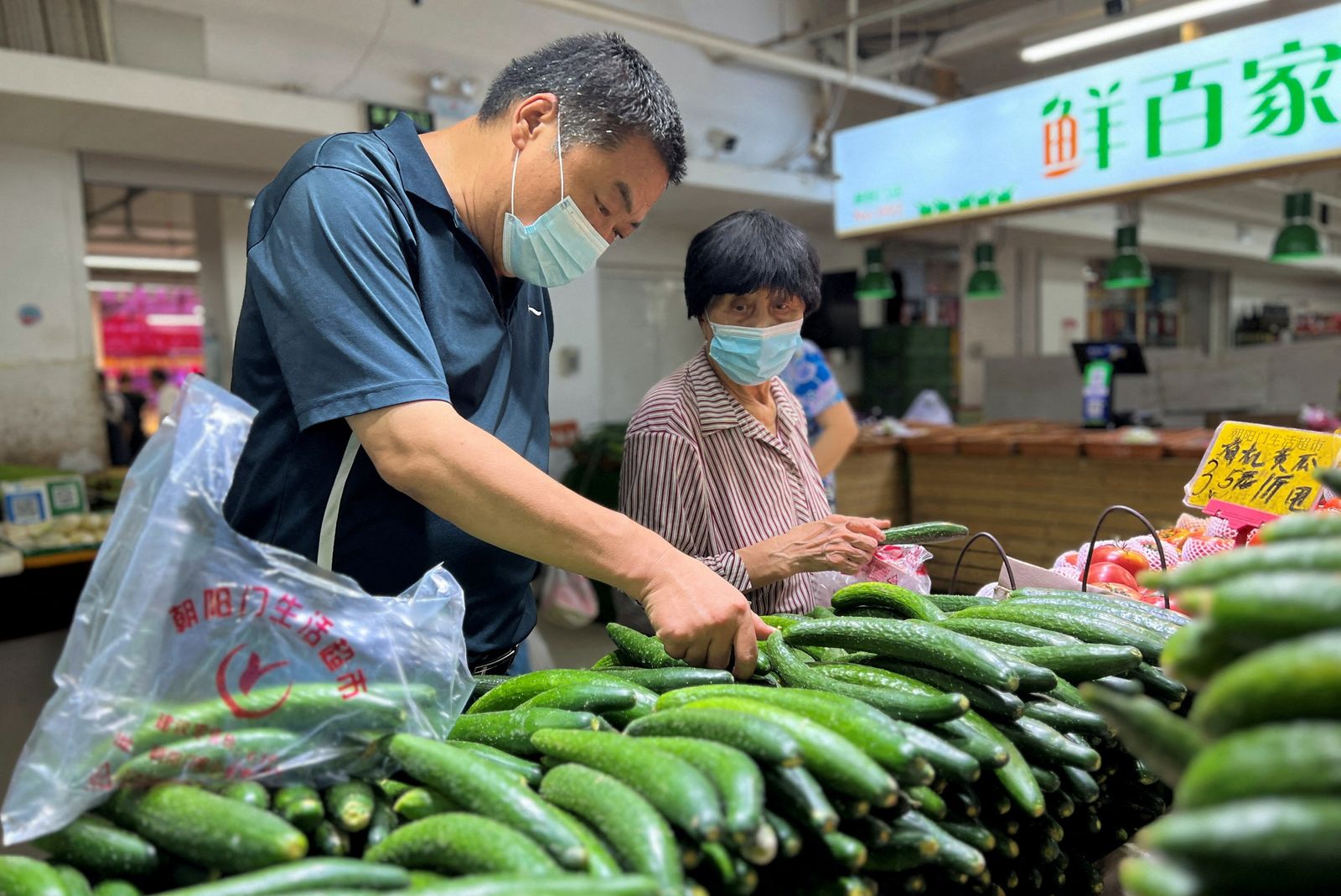 FILE PHOTO: Customers shop vegetables at a market in Beijing - REUTERS