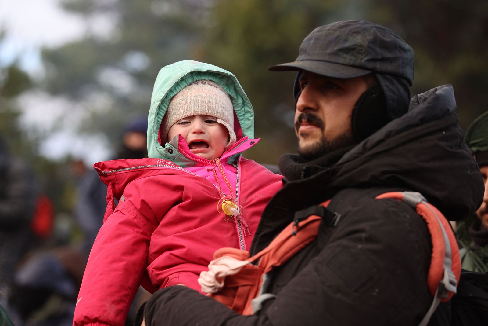 مهاجر يحمل طفلاً يبكي على حدود بيلاروسيا مع بولندا - 8 نوفمبر 2021 - AFP