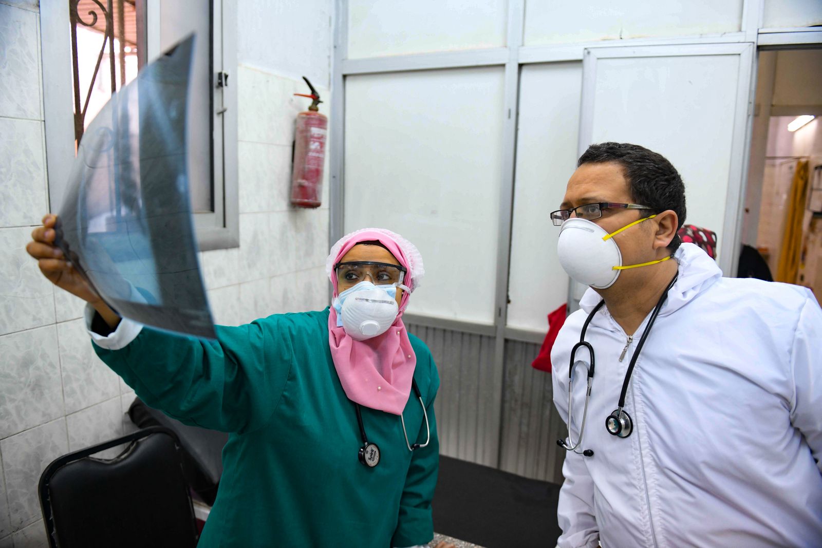 أطباء مصريون يفحصون أشعة لمريض في وحدة الأمراض المعدية بإحدى المستشفيات  - AFP