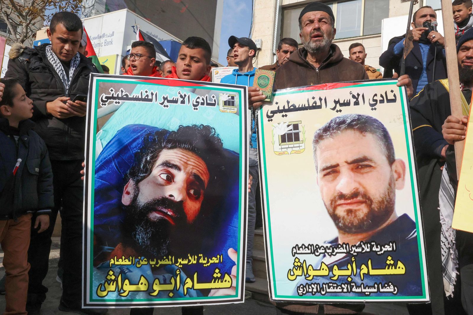 Supporters and relatives of hunger-striking Palestinian prisoner Hisham Abu Hawash, including his son Hadi (C L) rally in his village of Dura west of Hebron in the occupied West Bank, on January 2, 2022, to demand his release from Israeli detention without charges, as he teetered close to death after around 140 days of refusing food. (Photo by HAZEM BADER / AFP) - AFP