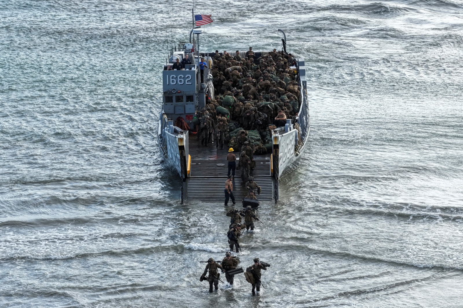 منظر جوي بطائرة مسيّرة يُظهر عناصر من مشاة البحرية الأميركية ينتشرون على الشاطئ عقب نزولهم من مركبة إنزال بحرية (LCU) خلال عمليات برمائية في بورتوريكو. 9 ديسمبر 2025