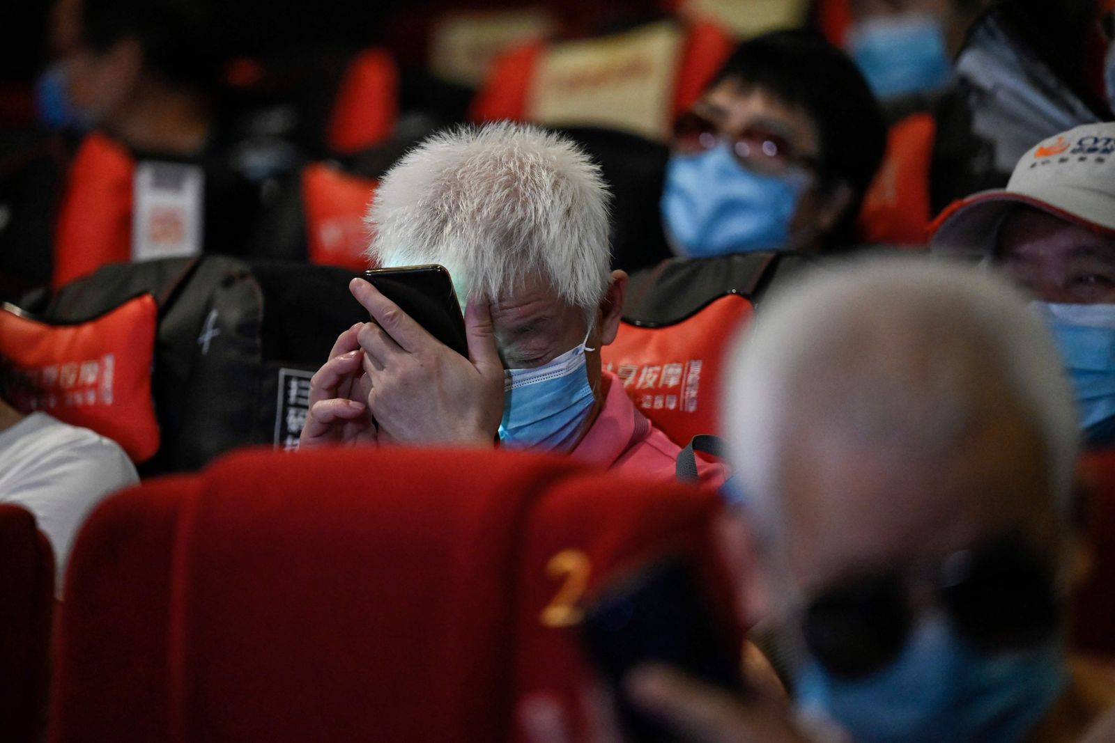 This photo taken on August 7, 2021 shows a visually impaired man listening to his phone at a cinema in Beijing. - Dozens of blind moviegoers come to the Saturday screenings organised by Xin Mu Theater, a small group of volunteers who were the first to introduce films to blind audiences in China. (Photo by Jade GAO / AFP) / To go with AFP story China-social-disabled-film, FEATURE by Poornima WEERASEKARA and Danni ZHU - AFP