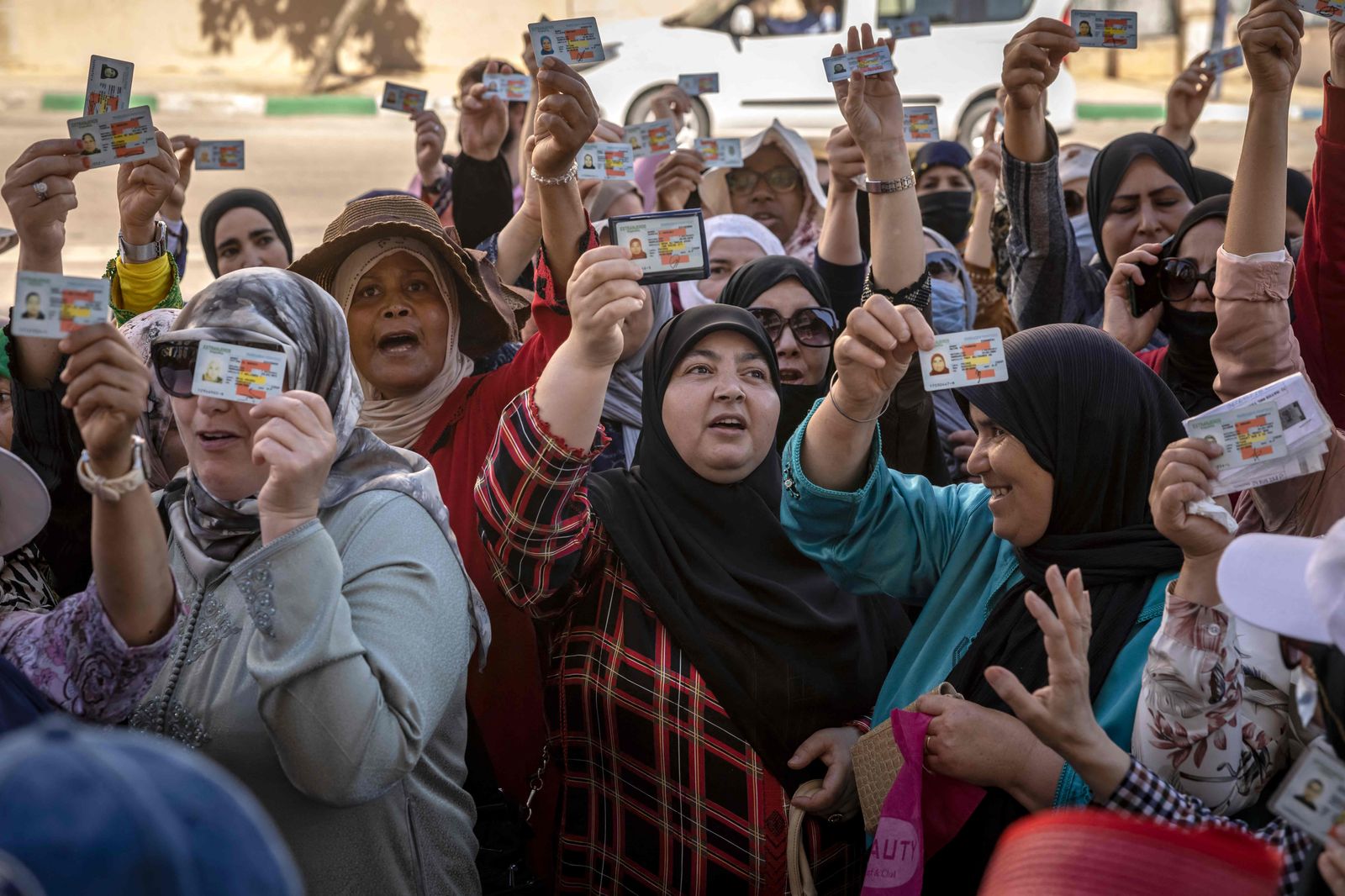 Moroccan workers gather with their work permits during a demonstration demanding the right to access the Spanish enclave of Ceuta without a visa, at Morocco's Fnideq border post on May 31, 2022. - Morocco and Spain have reopened the land borders between the north African country and the Spanish enclaves of Ceuta and Melilla, two years after they were shut due to Covid restrictions and a major diplomatic row. The reopening of the borders of the two enclaves initially remains limited to residents of Europe's open-borders Schengen area and their family members. (Photo by FADEL SENNA / AFP) - AFP